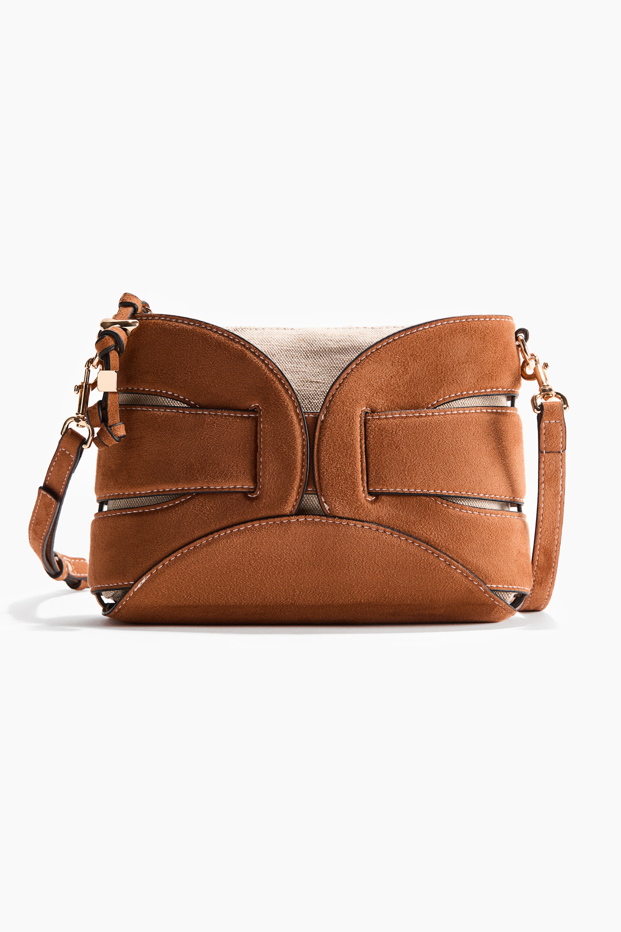 View larger image: A front-facing brown crossbody bag showcases curved suede-like panels forming an open 'H' design over a light beige woven canvas body. Two horizontal brown straps accentuate the center panels, while gold-toned hardware attaches the brown crossbody strap with visible light stitching.
