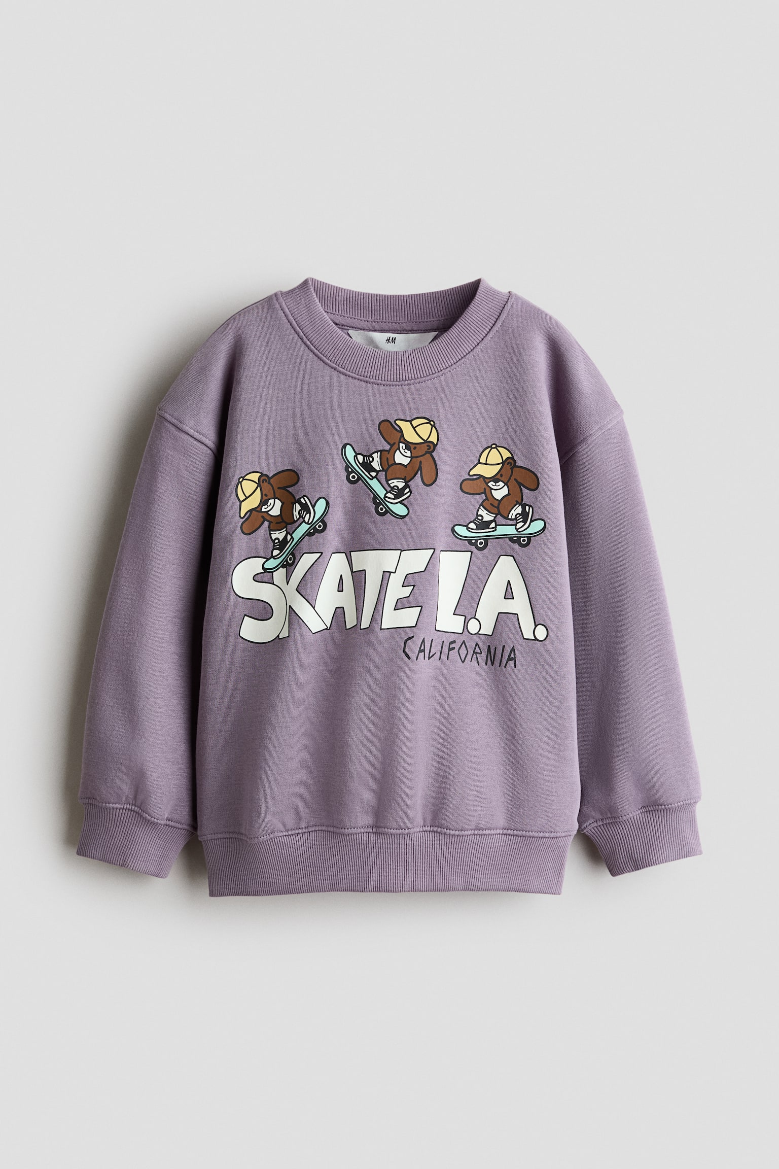 ÎÎ½Î± Î¼ÏÎ² ÏÎ¿ÏÏÎµÏ Î±ÏÏ ÏÏÎ±ÏÎ¼Î± sweatshirt ÏÎ±ÏÎ¿ÏÏÎ¹Î¬Î¶ÎµÏÎ±Î¹ ÏÎµ Î¼ÏÏÎ¿ÏÏÎ¹Î½Î® ÏÏÎ·, Î¼Îµ ÏÎ±Î»Î±ÏÎ® ÎµÏÎ±ÏÎ¼Î¿Î³Î®, ÏÎµÏÎ¼Î­Î½Î¿ÏÏ ÏÎ¼Î¿ÏÏ, ÏÎ¹Î¼Ï ÏÏÏÎ¿Î³Î³ÏÎ»Î® Î»Î±Î¹Î¼ÏÎºÎ¿ÏÎ·, ÏÎ¹Î¼Ï Î¼Î±Î½ÏÎ­ÏÎµÏ ÎºÎ±Î¹ ÏÎ¹Î¼Ï ÏÎµÎ»ÎµÎ¯ÏÎ¼Î±. Î¤Î¿ Î¼ÏÏÎ¿ÏÏÎ¹Î½Ï Î¼Î­ÏÎ¿Ï Î±Î½Î±Î´ÎµÎ¹ÎºÎ½ÏÎµÎ¹ Î­Î½Î± ÏÏÏÏÎ¼Î­Î½Î¿ Î³ÏÎ±ÏÎ¹ÎºÏ Î¼Îµ ÏÏÎµÎ¹Ï ÎºÎ±ÏÏÎ¿ÏÎ½Î¯ÏÏÎ¹ÎºÎµÏ Î±ÏÎºÎ¿ÏÎ´ÎµÏ ÏÎ¿Ï ÎºÎ¬Î½Î¿ÏÎ½ skateboard, ÏÎ¬Î½Ï Î±ÏÏ ÏÎ¿ ÎºÎµÎ¯Î¼ÎµÎ½Î¿ Â«SKATE L.A. CALIFORNIAÂ».