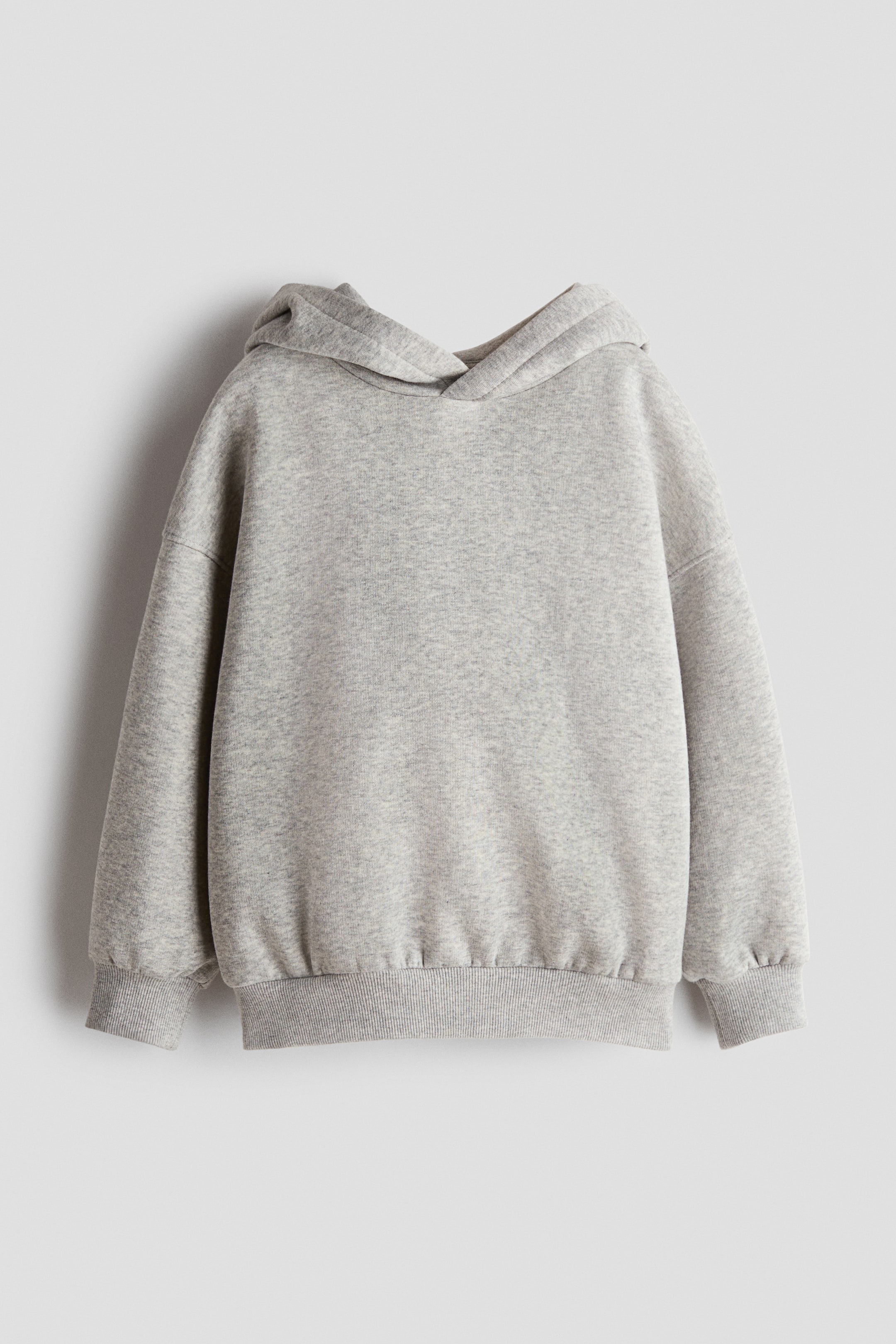 Größeres Bild anzeigen: Ein grauer Hoodie aus Fleece-Sweatshirtstoff ist von vorne zu sehen und verfügt über eine gefütterte Kapuze mit überlappender Vorderseite, überschnittene Schultern sowie Rippbündchen an den Ärmelabschlüssen und am Saum.