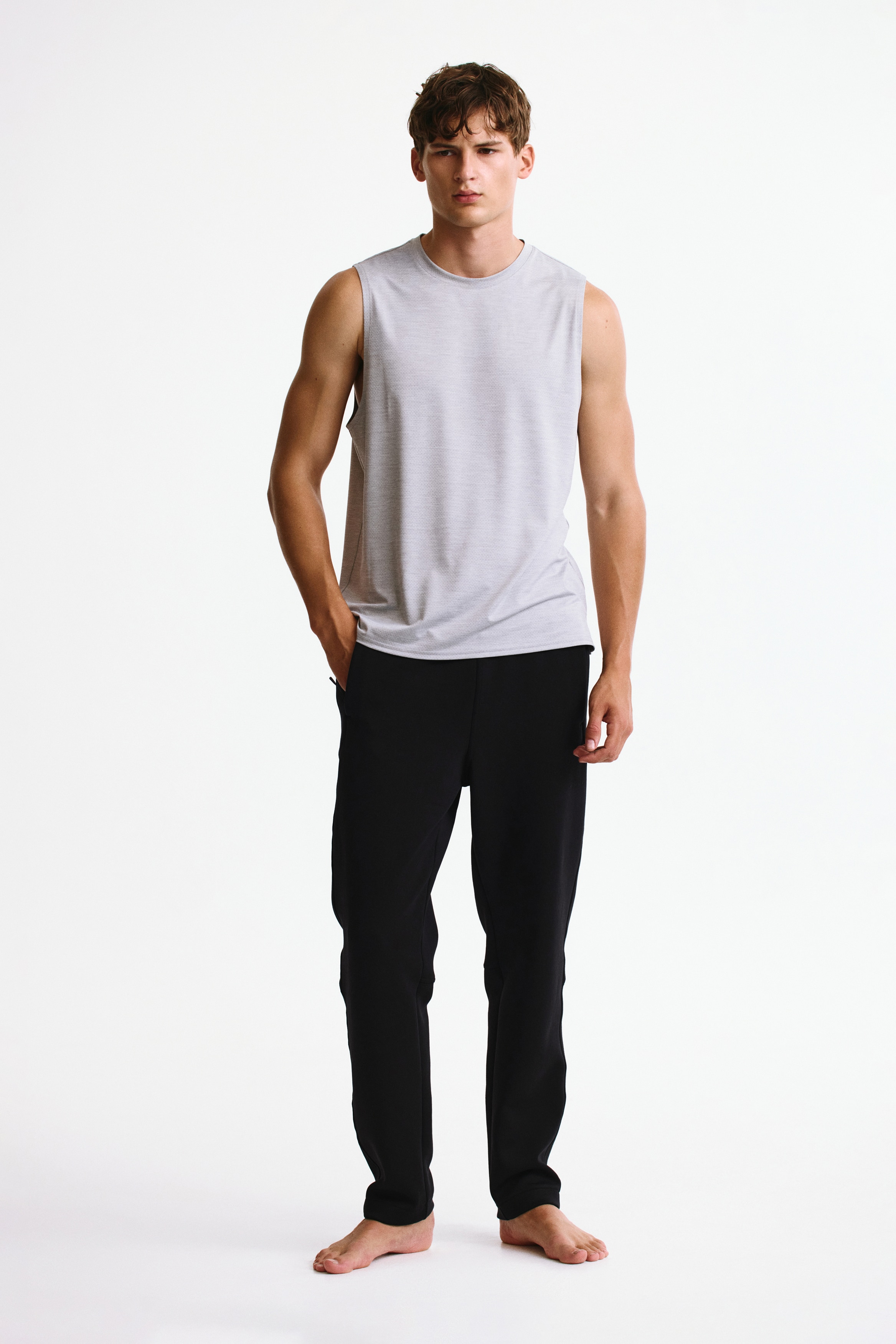 Black trousers come with an elasticated waistband and side pockets, with the left pocket featuring a zipper closure. A subtle "DO R" text appears on the right thigh, and the trouser hems are plain.