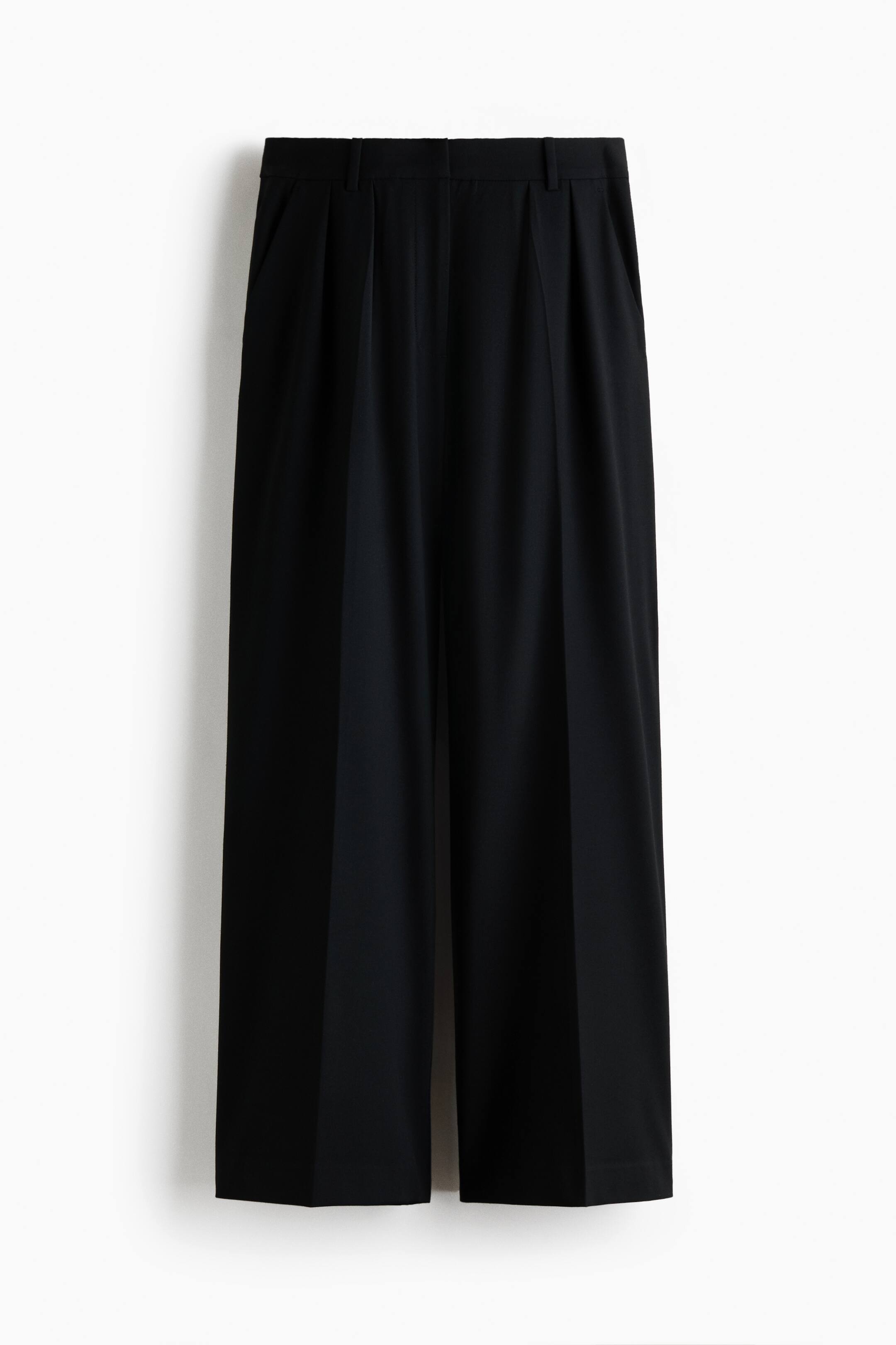 View larger image: Black wide-leg trousers are hanging facing the front, featuring a structured waistband with belt loops and front pleats. The trousers are displaying sharp pressed creases running down the center of each wide leg.