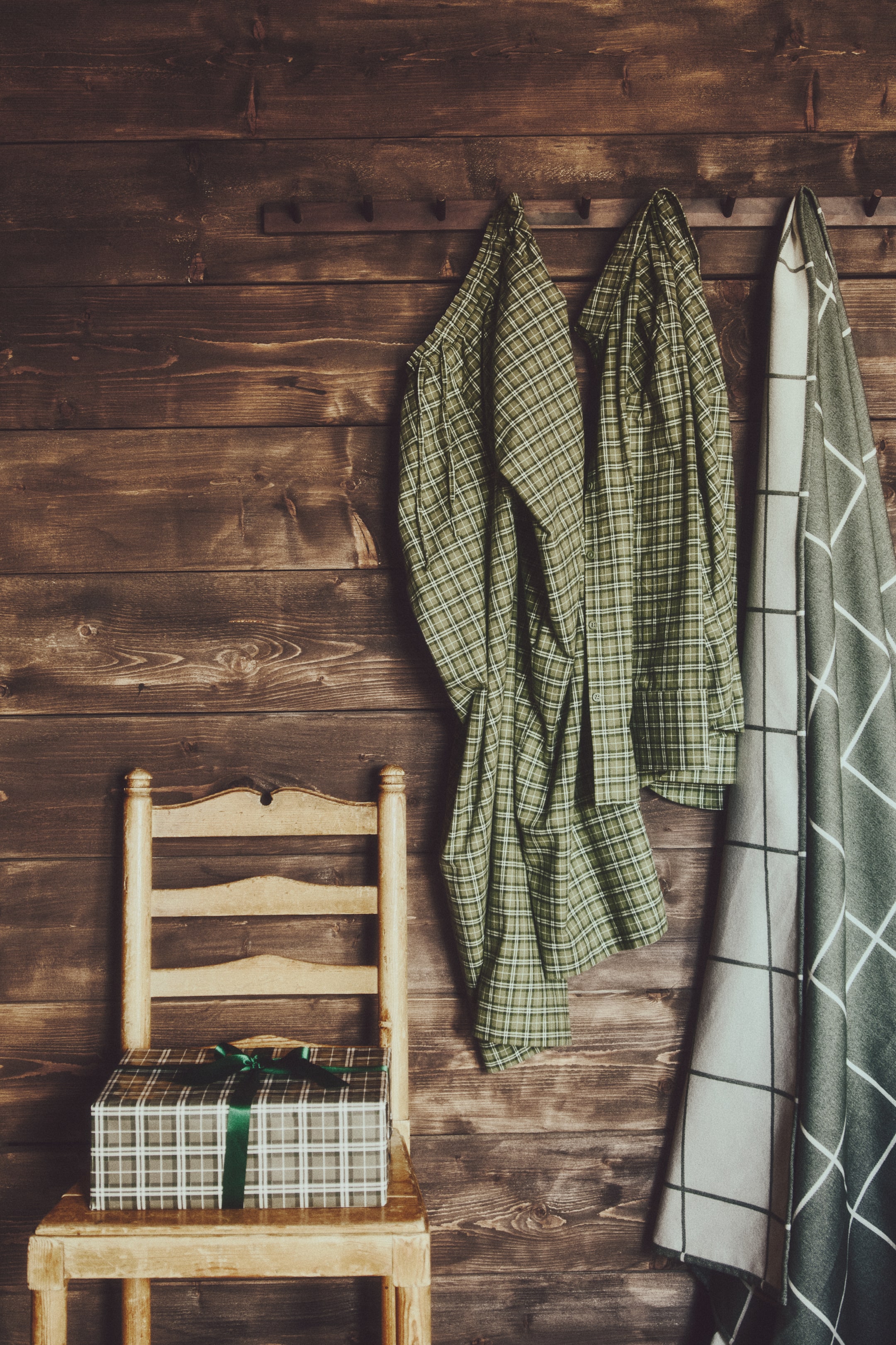 Voir une image plus grande: Un ensemble de pyjama à carreaux vert et blanc, composé d'une chemise à manches longues boutonnée et d'un pantalon assorti, est suspendu à un porte-crochets. La chemise présente un col classique et une fermeture boutonnée sur le devant, tandis que le pantalon à coupe décontractée est drapé à côté.