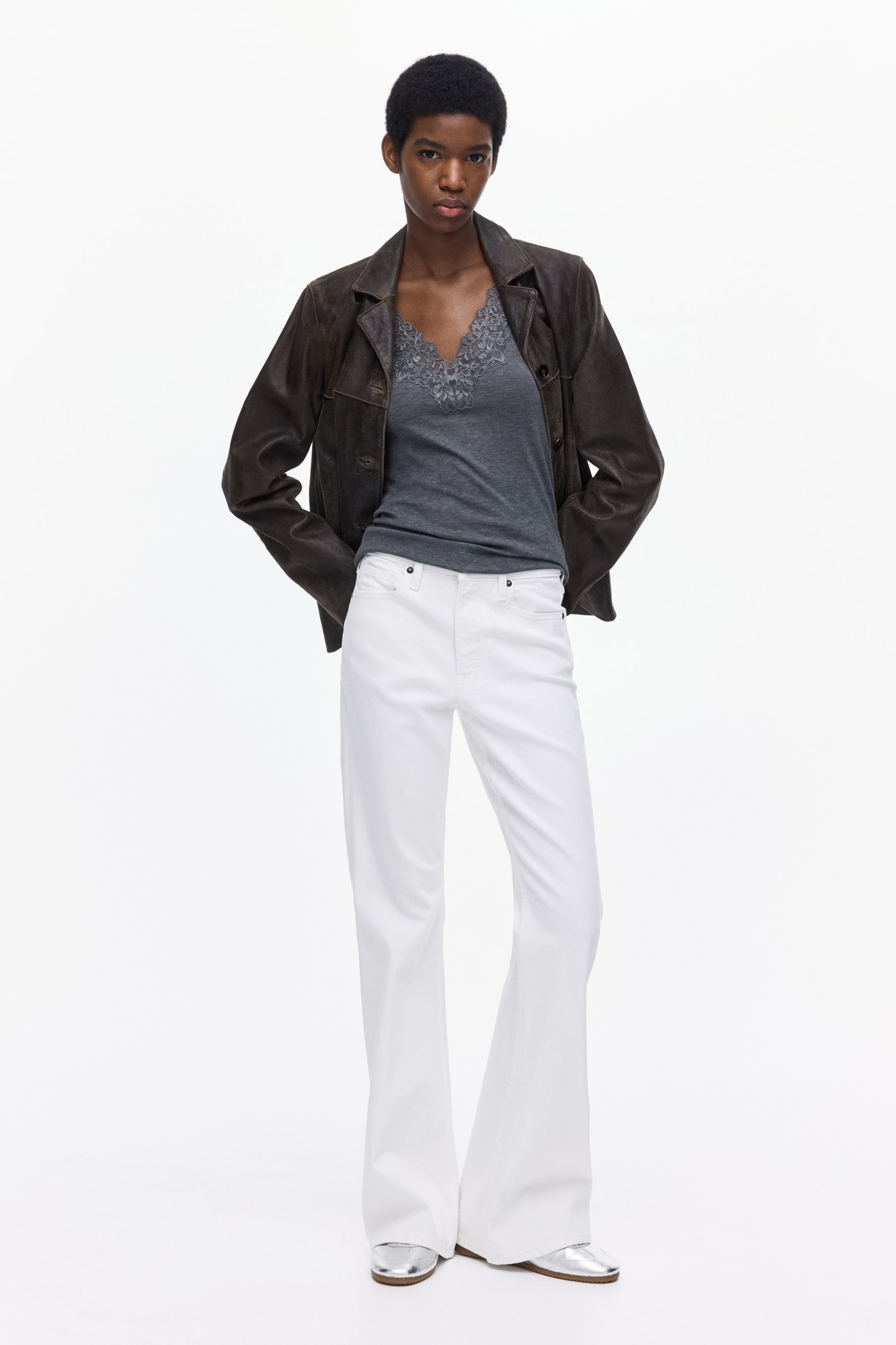 Agrandir l'image: Les pantalons évasés blancs présentent une coupe longue à jambe large, des poches avant visibles et des rivets, et sont présentés de face.