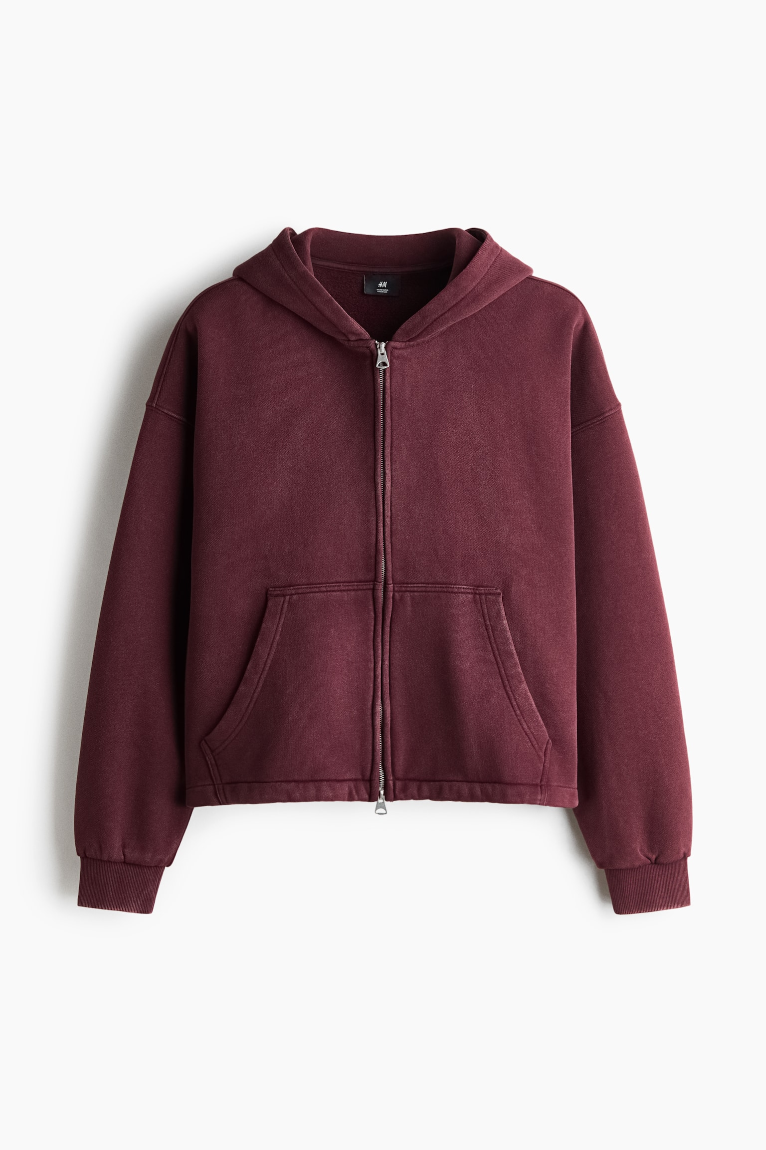 A boxy-style zip-through hoodie in a deep burgundy colour is displayed facing forward, showcasing its oversized silhouette. The hoodie features a lined hood, dropped shoulders, long sleeves with ribbed cuffs, a split front pocket, and a silver two-way zip.