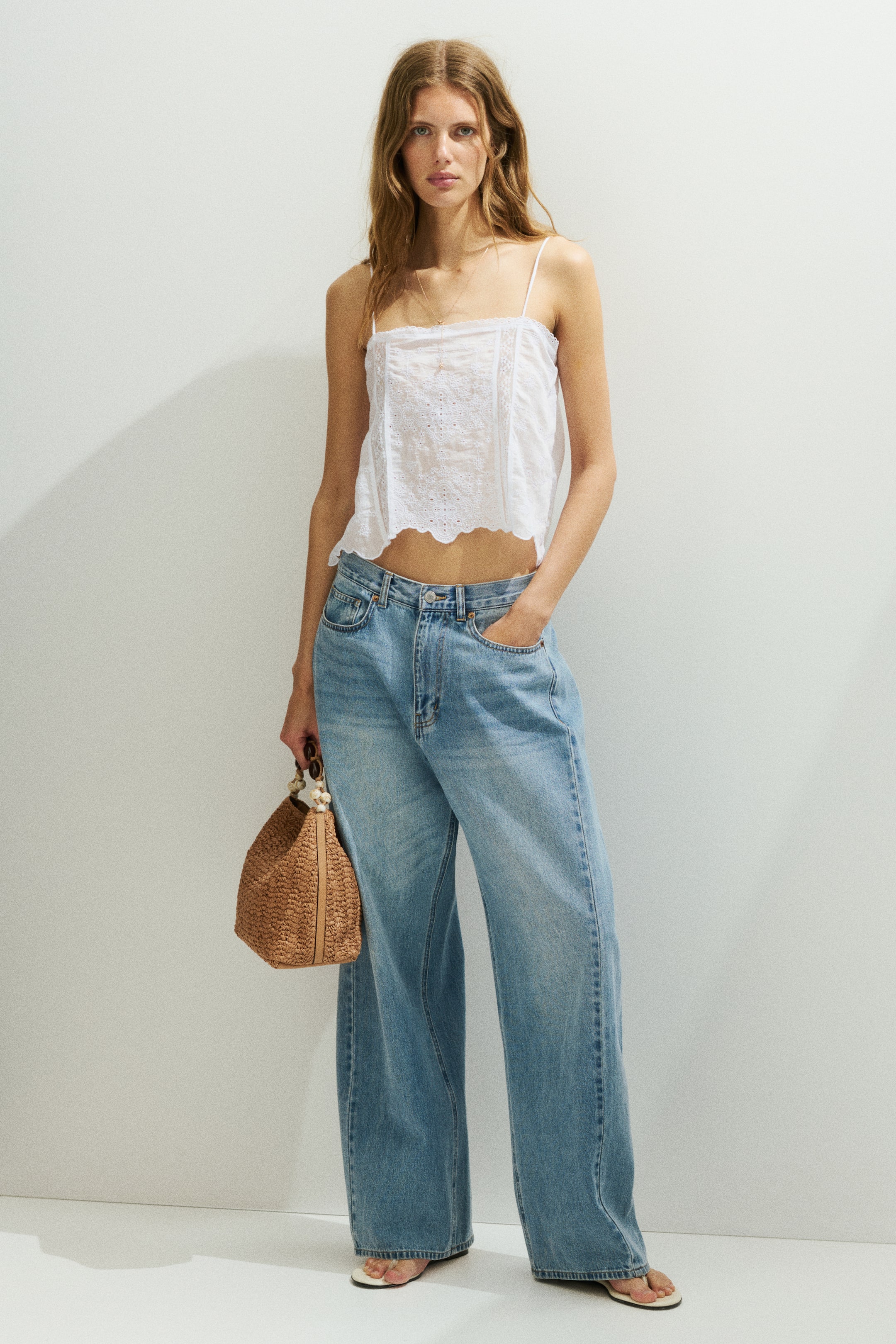 View larger image: Light blue wide-leg jeans exhibit a laid-back, loose fit when viewed from the front. They come with a button and zipper fly closure, front pockets, and a long hem that elegantly gathers at the feet.