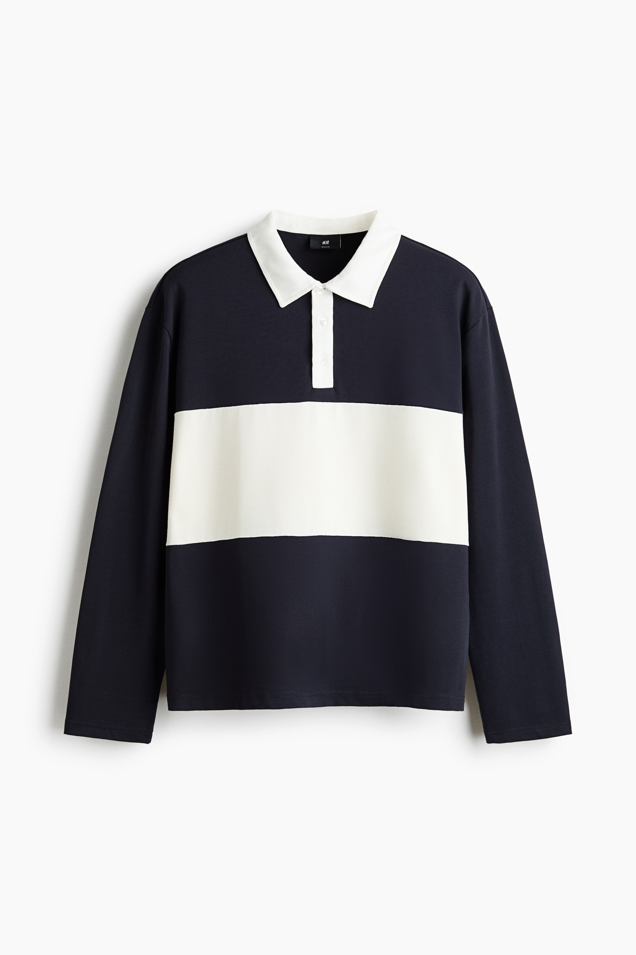 Grotere afbeelding bekijken: Een rugbyshirt wordt frontaal gepresenteerd, met een marineblauwe body en een brede off-white horizontale streep over de borst. Het is ontworpen met een witte puntkraag, een drieknoopssluiting, lange mouwen met verlaagde schouders en een recht gesneden zoom, en heeft een normale pasvorm.