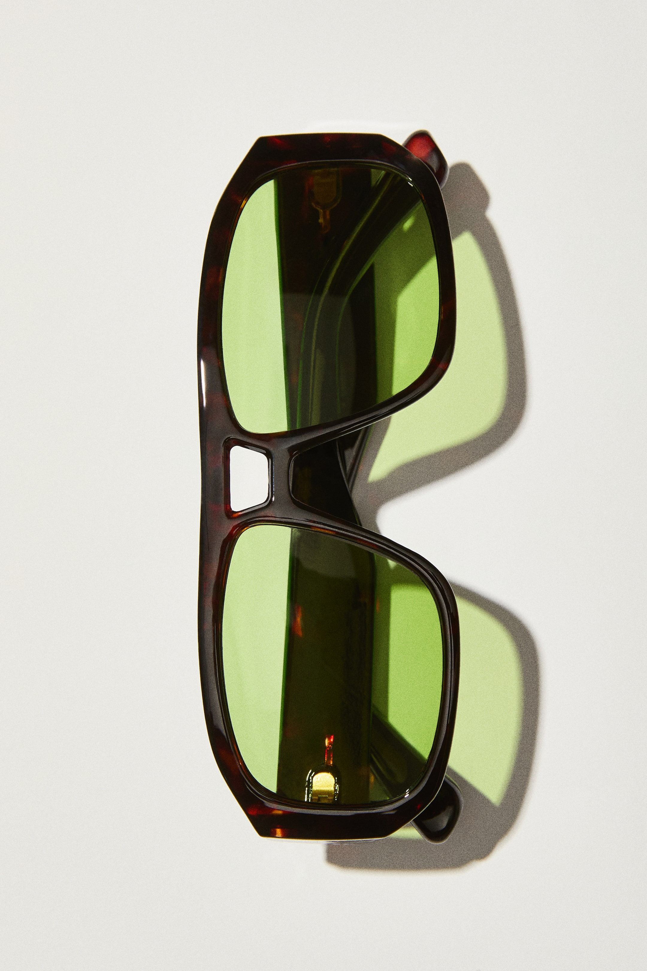 View larger image: Aviator-style sunglasses are positioned facing forward, showcasing a dark tortoiseshell plastic frame with broad sidepieces. They are fitted with green polarized lenses, and a small gold-colored metal accent is noticeable on the temple arm.