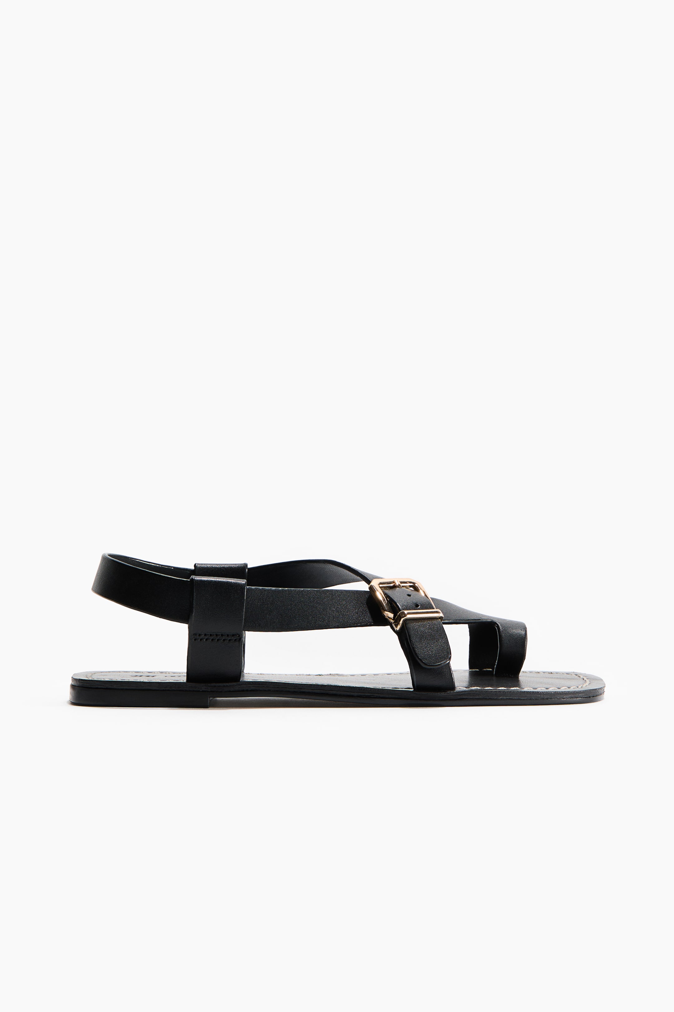 Größeres Bild anzeigen: Ein schwarzer Sandale wird in einer Seitenansicht präsentiert, die mehrere glatte Riemen aufweist, darunter einen breiten Slingback-Riemen und Kreuzriemen über dem Vorderfuß, mit einer Zehenschlaufe. Eine goldfarbene rechteckige Schnalle sichert einen der vorderen Riemen, und die flache schwarze Sohle zeigt sichtbare Nähte entlang ihrer Kante.