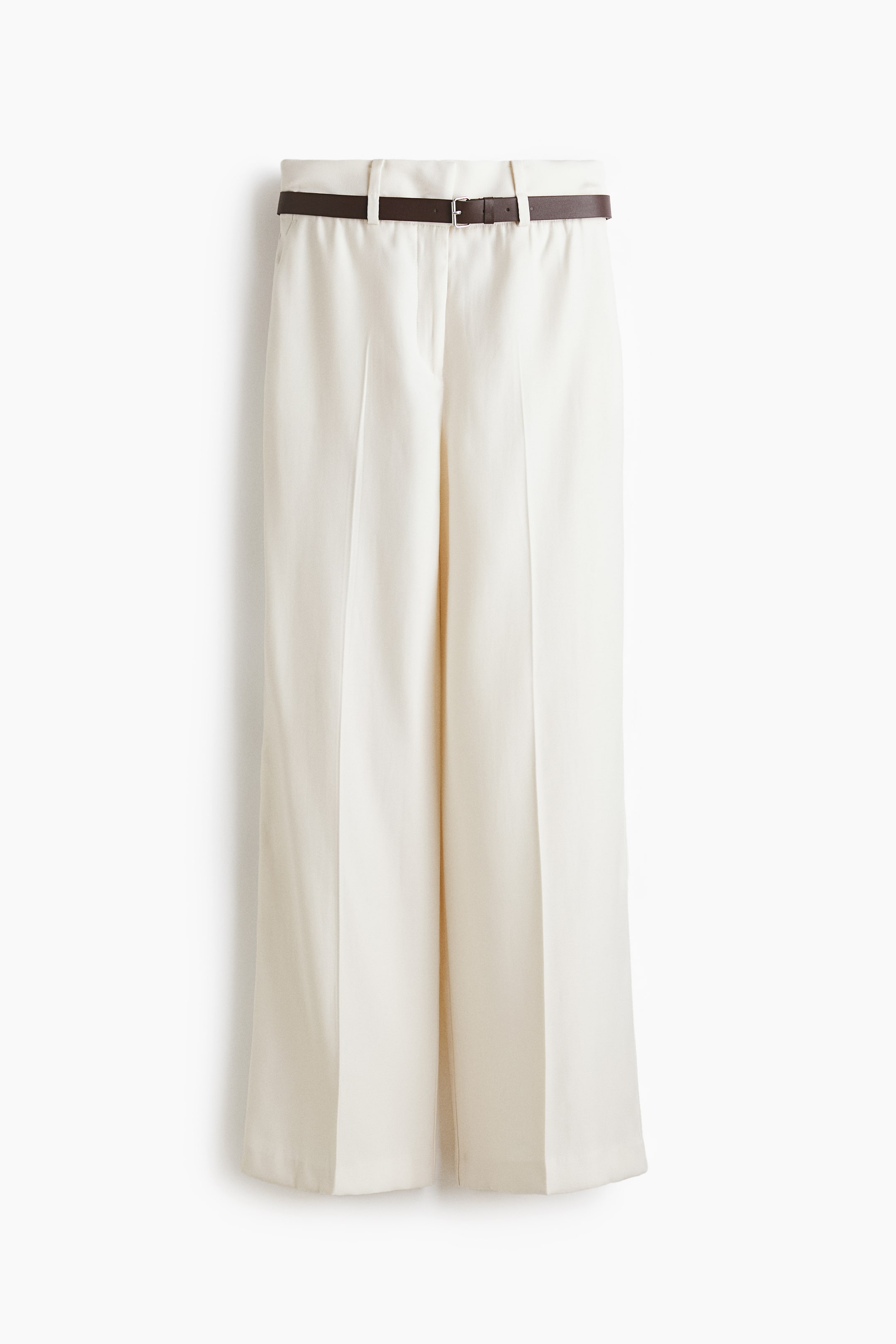 View larger image: The off-white wide-leg trousers showcase a flat front with pressed creases running down each leg. A slim, dark brown belt with a silver-toned buckle is threaded through the belt loops.