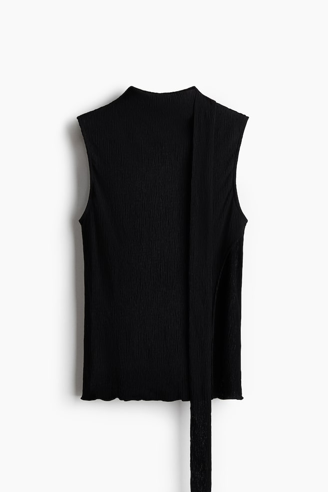 Ein schwarzes, ärmelloses Top zeigt die VORDERSEITE und verfügt über einen Mockneck sowie eine durchgehende Crinkle-Textur im Stoff. Ein langes, schmales Bindeband verläuft von der Ausschnittkante an der rechten Seite nach unten, und der untere Saum weist eine wellige Abschlusskante auf. - 1