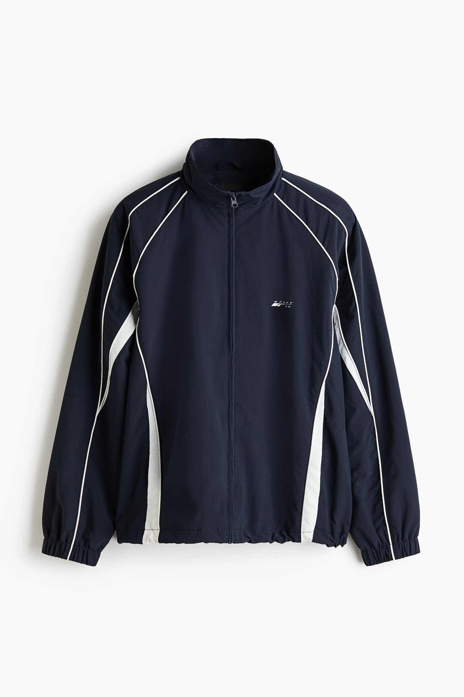 A navy blue track jacket is presented with a full-zip front, a stand-up collar, and a small white logo on the left chest. It features white piping along the raglan seams and white side panels, complete with elasticated cuffs and hem. - 1