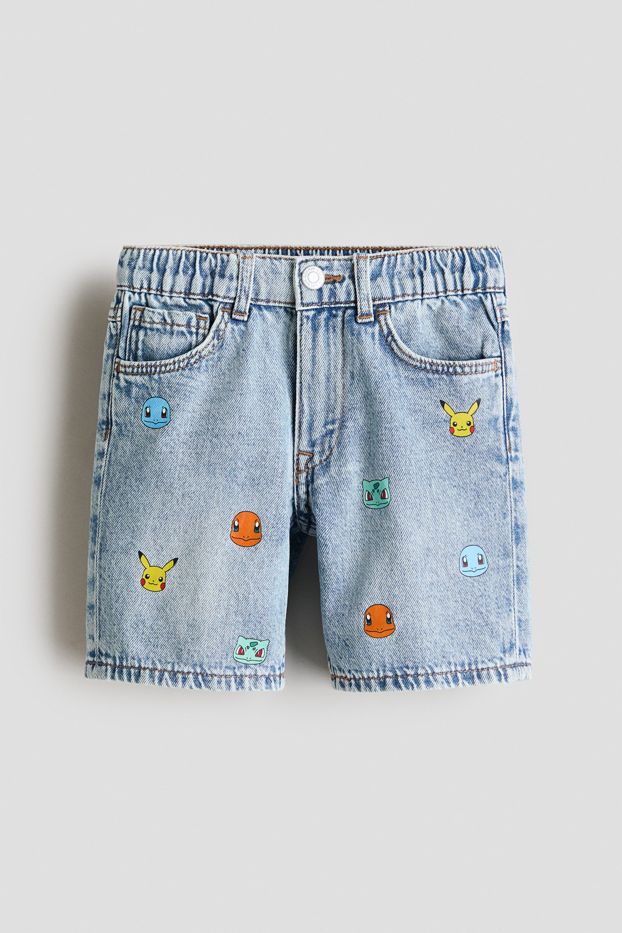 Größeres Bild ansehen: Die 5-Pocket-Shorts präsentieren sich von vorne aus hellblau bedrucktem Baumwoll-Denim. Sie zeichnen sich durch einen Allover-Print mit bunten Cartoon-Gesichtern, einen verstellbaren elastischen Bund und einen Reißverschluss mit Druckknopfverschluss aus.