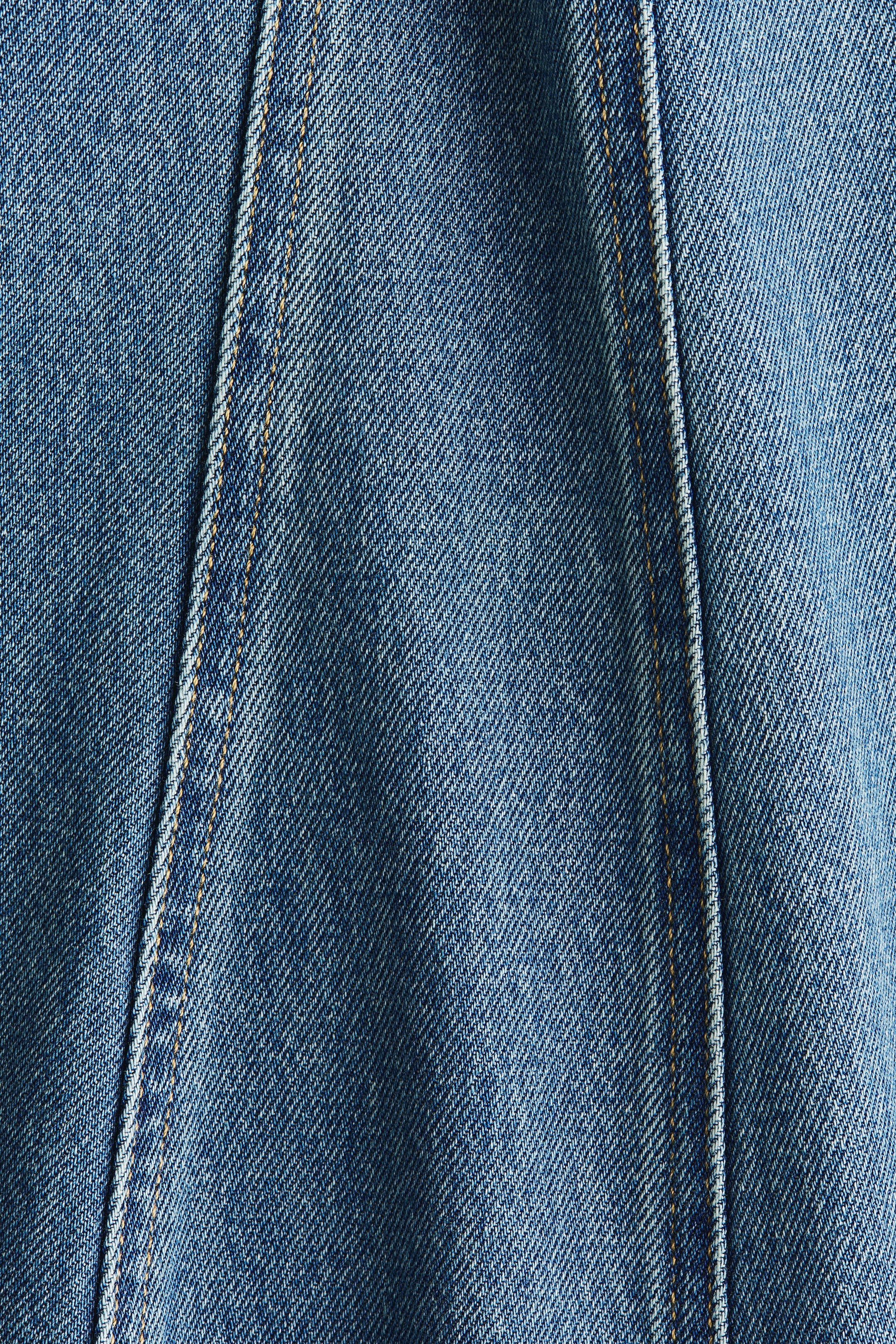 Größeres Bild anzeigen: Der blaue Baumwoll-Denim des Kleides zeigt eine sichtbare vertikale Naht mit orange-brauner Ziernaht.