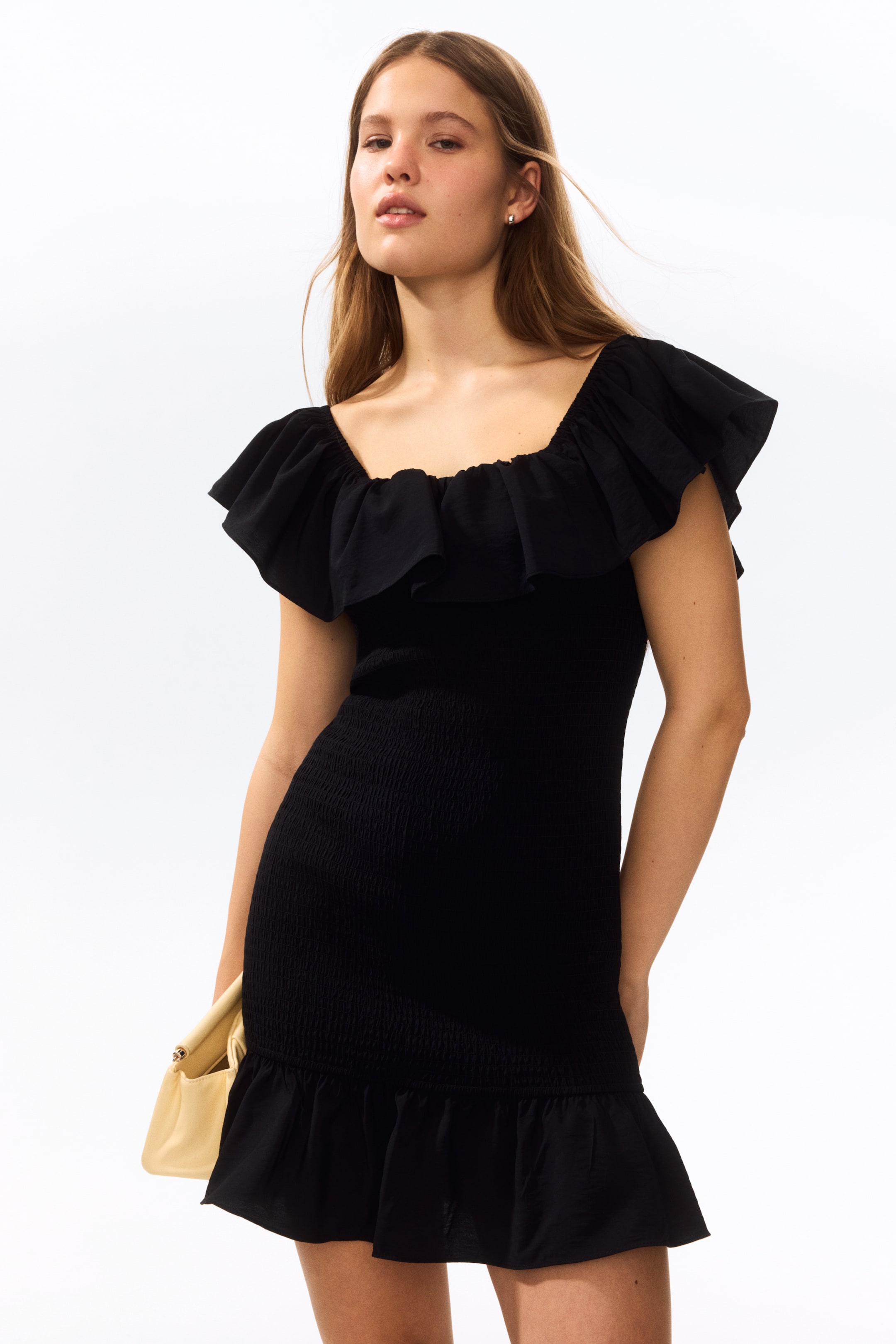 View larger image: A black mini dress featuring a square neckline with ruffled detailing extending into cap sleeves. Its bodice and skirt are smocked, ending with a ruffled hemline.