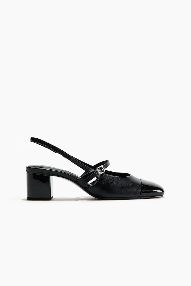Une chaussure slingback en cuir noir met en valeur une tige en cuir mat avec un bout verni brillant et un talon bloc assorti. La chaussure prÃ©sente une bride de cou-de-pied rÃ©glable avec boucle argentÃ©e ainsi quâune bride arriÃ¨re slingback, vue de profil. - 1