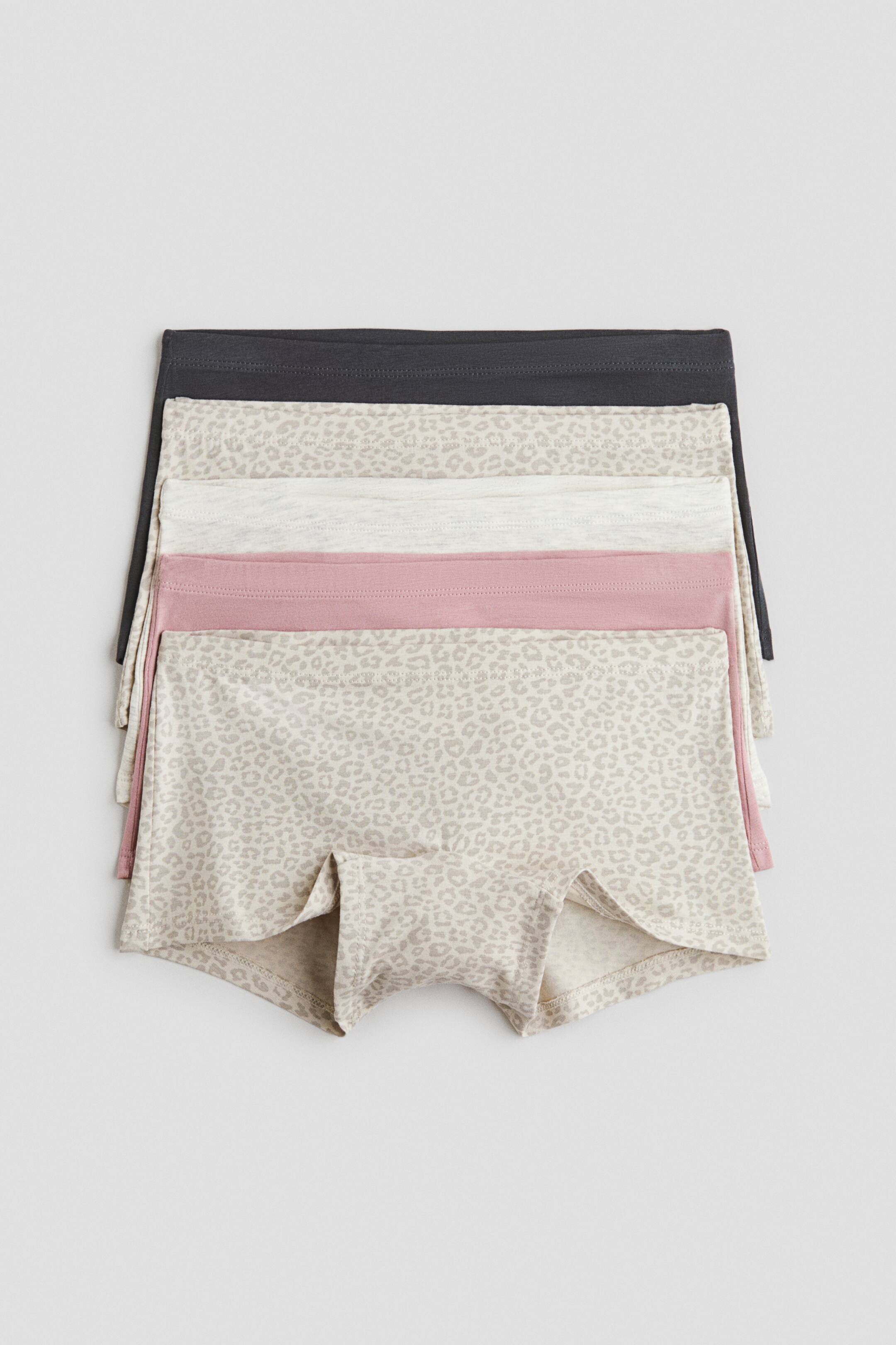 Vis større bilde: Fem par boyshorts er stablet horisontalt og viser ulike farger og mønstre, inkludert en mørk grå, en lys leopardprint, en lys grå, en rosa og enda en lys leopardprint. Det nederste paret viser benåpningene og det foldede skrittområdet.