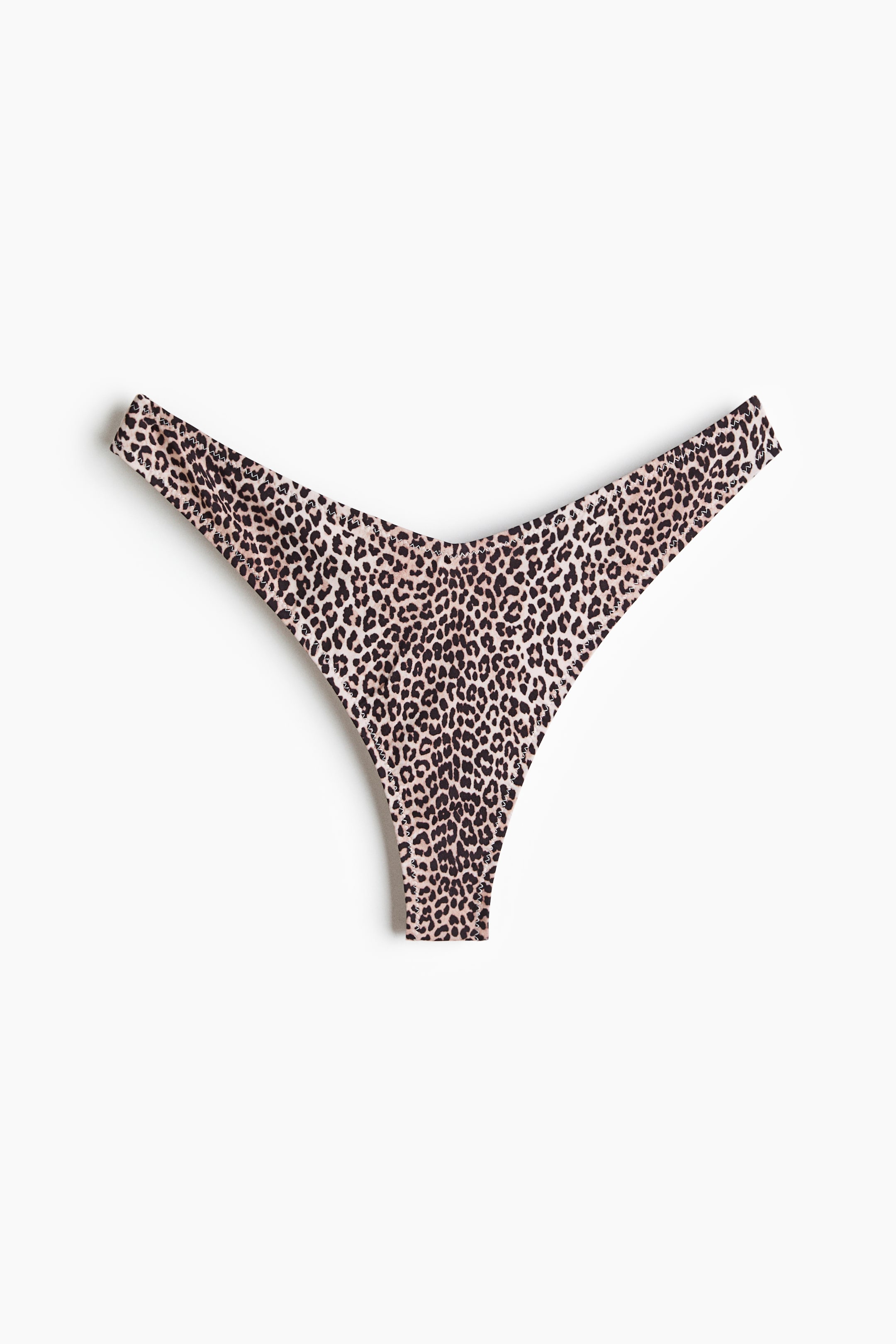 View larger image: A thong bikini bottom with a low, V-shaped waist is shown from the front, featuring a leopard print pattern with black spots on a light beige background.