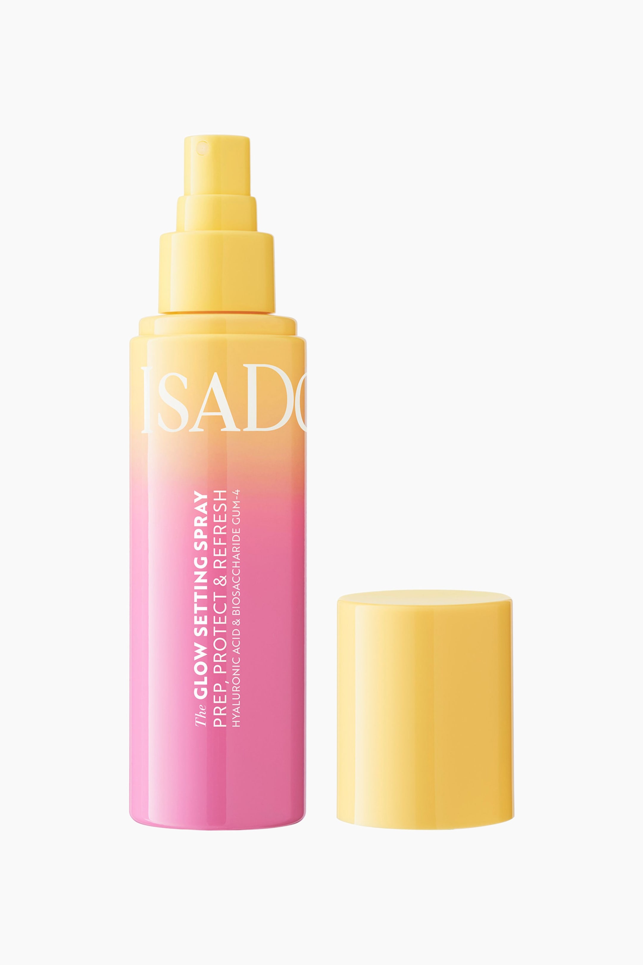 Vis større bilde: En sprayflaske står oppreist, med en gul-til-rosa fargegradient og en gul spraytopp. Hvit tekst med påskriften «The Glow Setting Spray» står vertikalt på flasken, og et separat gult sylinderformet lokk ligger ved siden av.