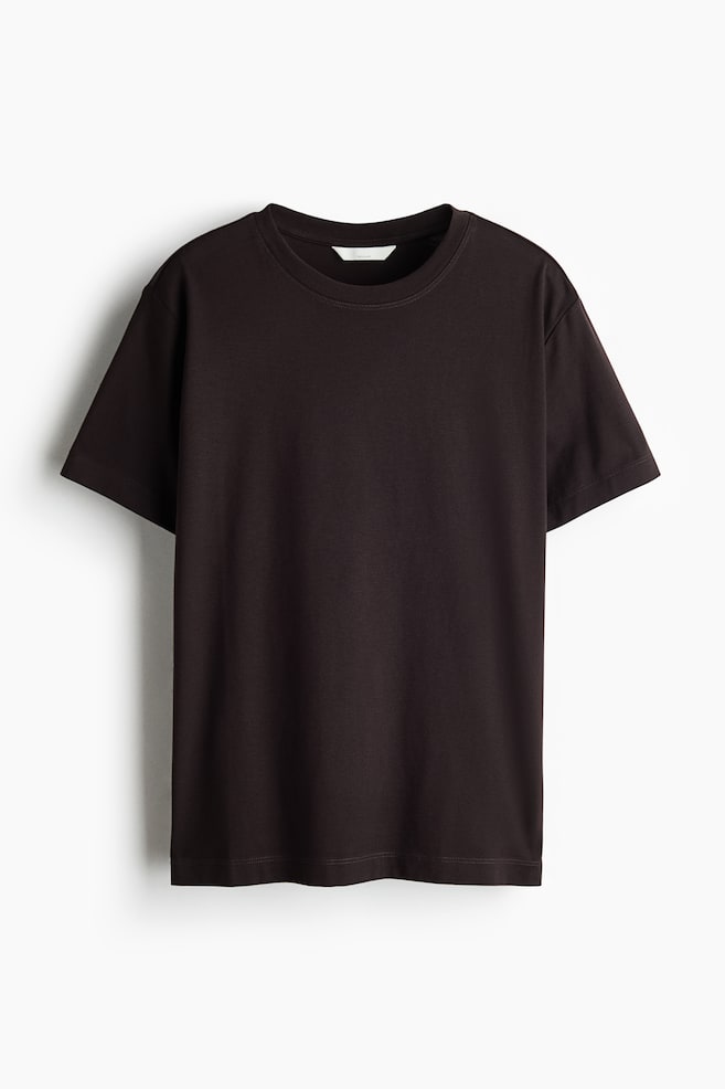 A dark brown cotton jersey T-shirt is hanging in a front view, showing a round, rib-trimmed neckline, short sleeves, and a straight-cut hem. - 1