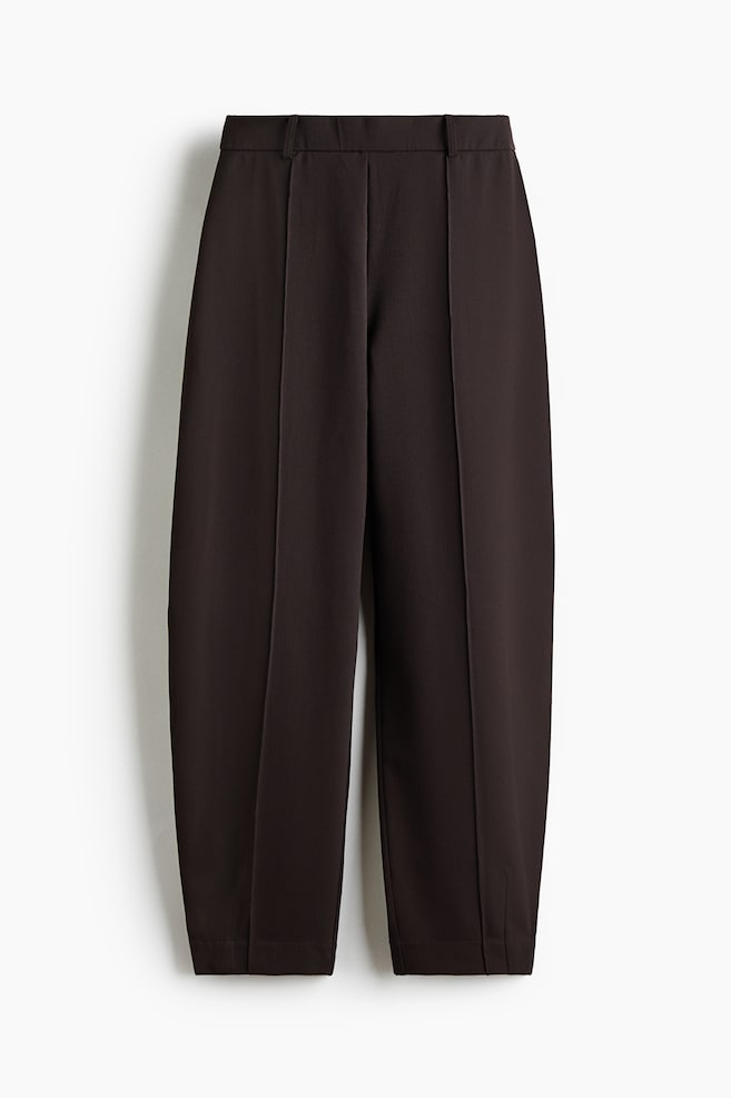 Dark brown trousers are presenting from the front, featuring a flat waistband with belt loops. Prominent vertical pintucks are running down the center front of each wide, cropped leg, which is finishing with a clean hem. - 1
