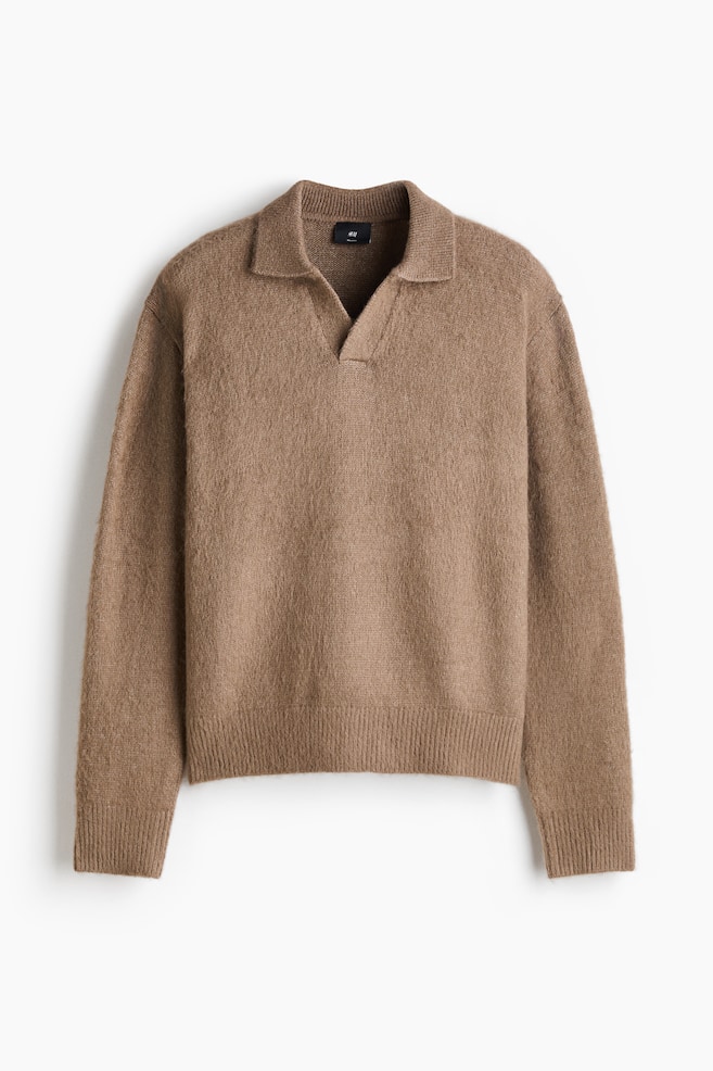 The light brown, fuzzy knit polo sweater is facing front, displaying a relaxed silhouette with drop shoulders. It is featuring an open Johnny collar, long sleeves with ribbed cuffs, and a ribbed hem. - 1