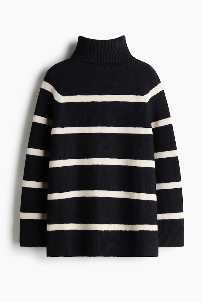 A black and white striped knitted jumper is shown from the front, featuring a high ribbed roll neck, long raglan sleeves, and a relaxed silhouette. The jumper displays horizontal off-white stripes across the body and sleeves, finishing with a ribbed hem and cuffs. - 1