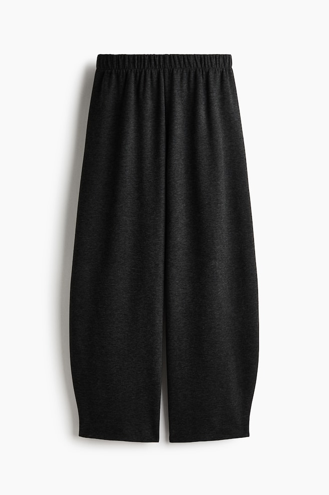 A pair of dark grey heather wide-leg trousers is shown from the front, featuring a high, gathered elasticated waistband. The soft knit fabric drapes down into a relaxed, voluminous silhouette with wide legs. - 1