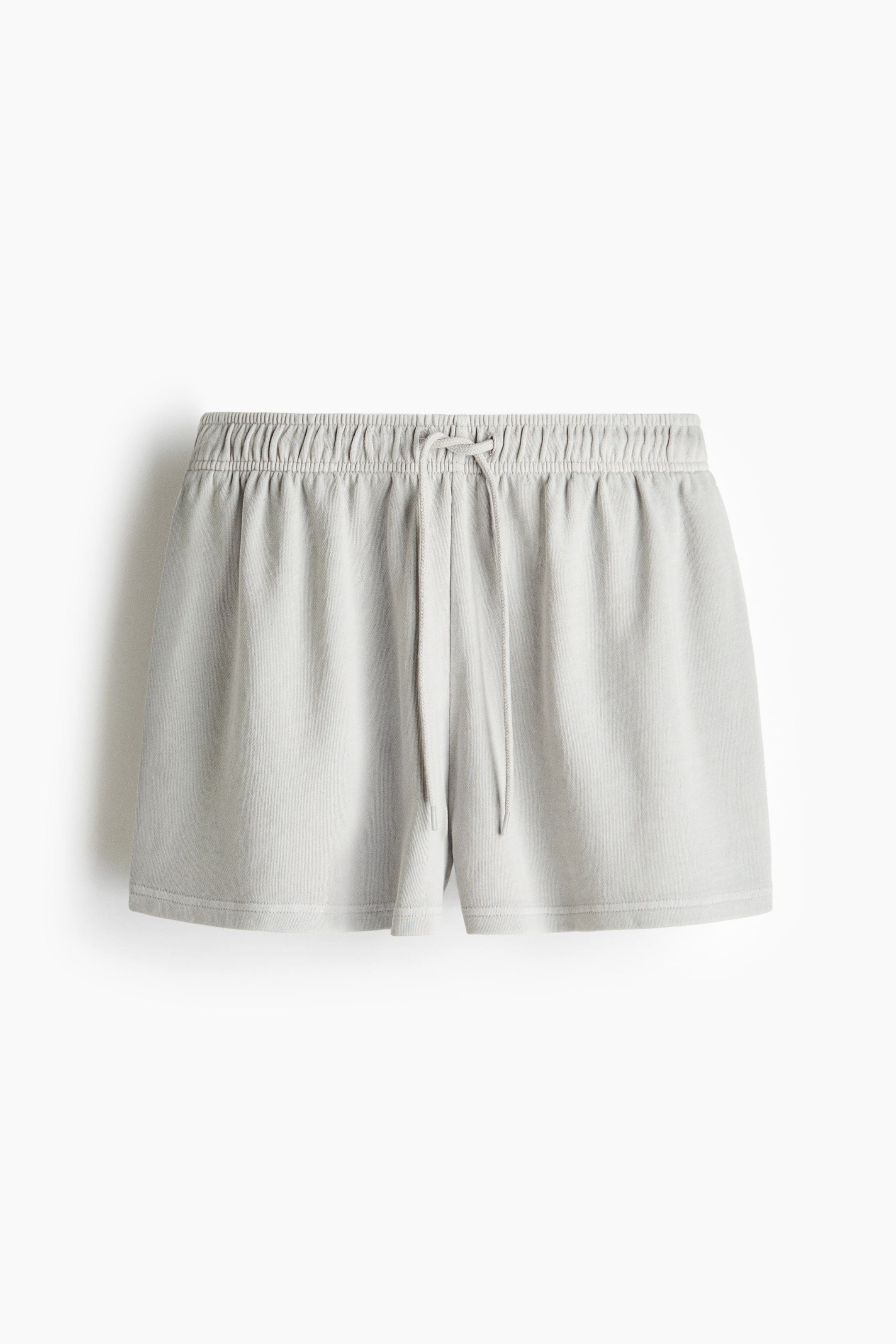 View larger image: Loose-fit shorts crafted from lightweight sweatshirt fabric feature an elasticated, drawstring waist, with the drawstring tied in a bow. Visible diagonal side pockets add functionality, and the shorts are showcased from the front.