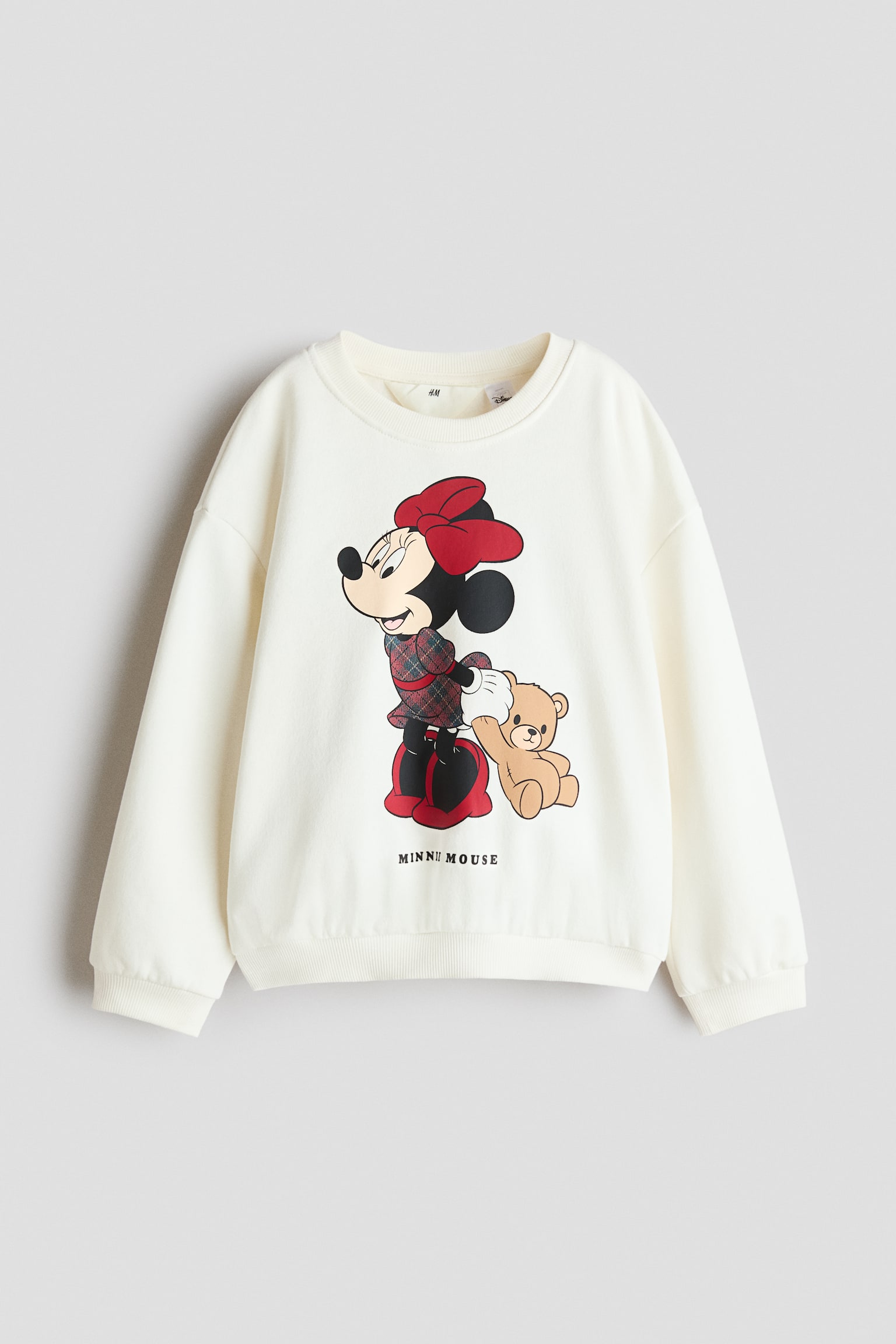 Egy tÃ¶rtfehÃ©r, oversize pulÃ³ver elÃ¶lnÃ©zetbÅl lÃ¡thatÃ³, amelyen Minnie egÃ©r egy mackÃ³t tartÃ³ grafikai printje szerepel, alatta a âMINNIE MOUSEâ felirattal. A pulÃ³ver bordÃ¡zott kerek nyakkivÃ¡gÃ¡ssal, leejtett vÃ¡llakkal, hosszÃº ujjakkal, valamint bordÃ¡zott alsÃ³ szegÃ©llyel Ã©s mandzsettÃ¡kkal kÃ©szÃ¼lt.