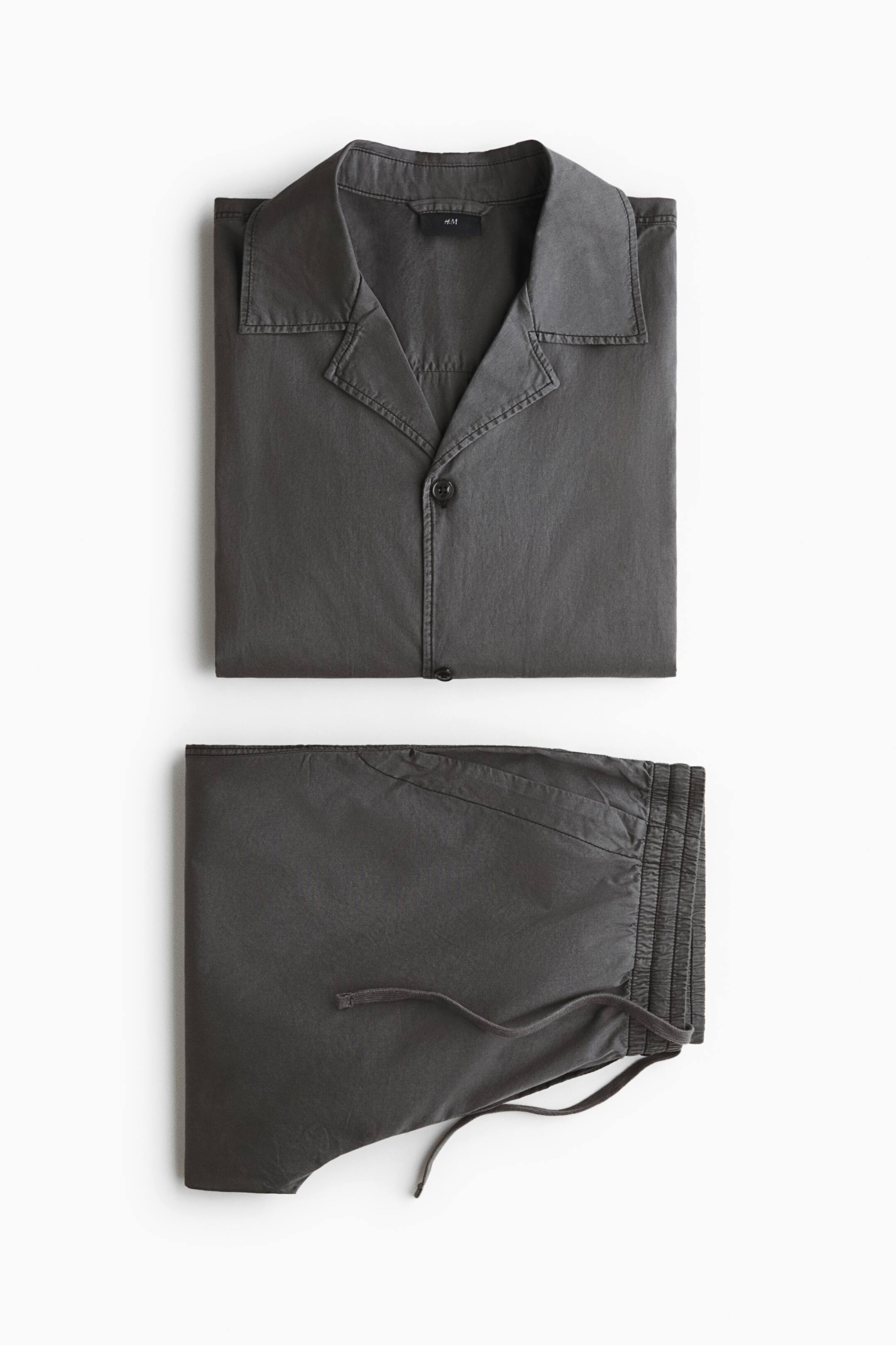 View larger image: A dark grey two-piece lounge set is laid flat, featuring a folded button-down shirt with a camp collar and matching folded trousers with an elasticated drawstring waistband.