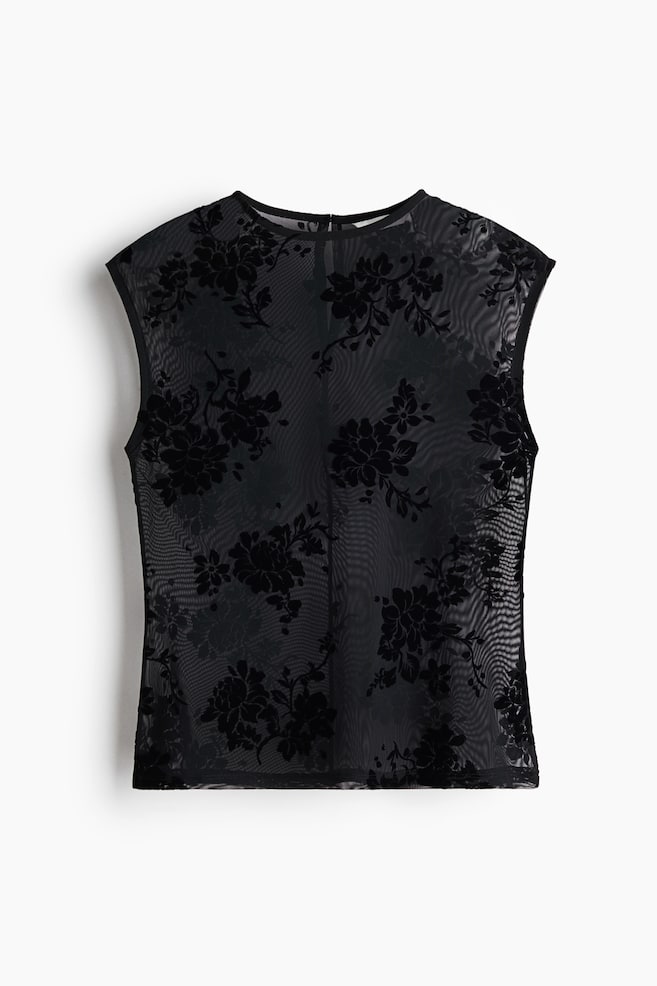 Un top entallado sin mangas en malla negra translúcida presenta un patrón floral afelpado negro en toda la prenda, visto de frente. El top cuenta con escote redondo, sisas rematadas y basta recta. - 1