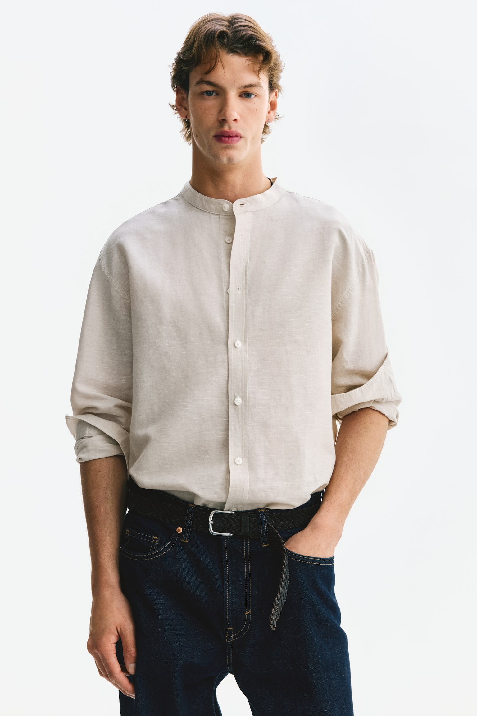 A light-coloured, relaxed-fit shirt is displaying its front, showcasing a band collar, a classic button-front placket with white buttons, long sleeves with buttoned cuffs, and a rounded hem. The shirt is showing a visibly textured linen and cotton blend fabric. - 1