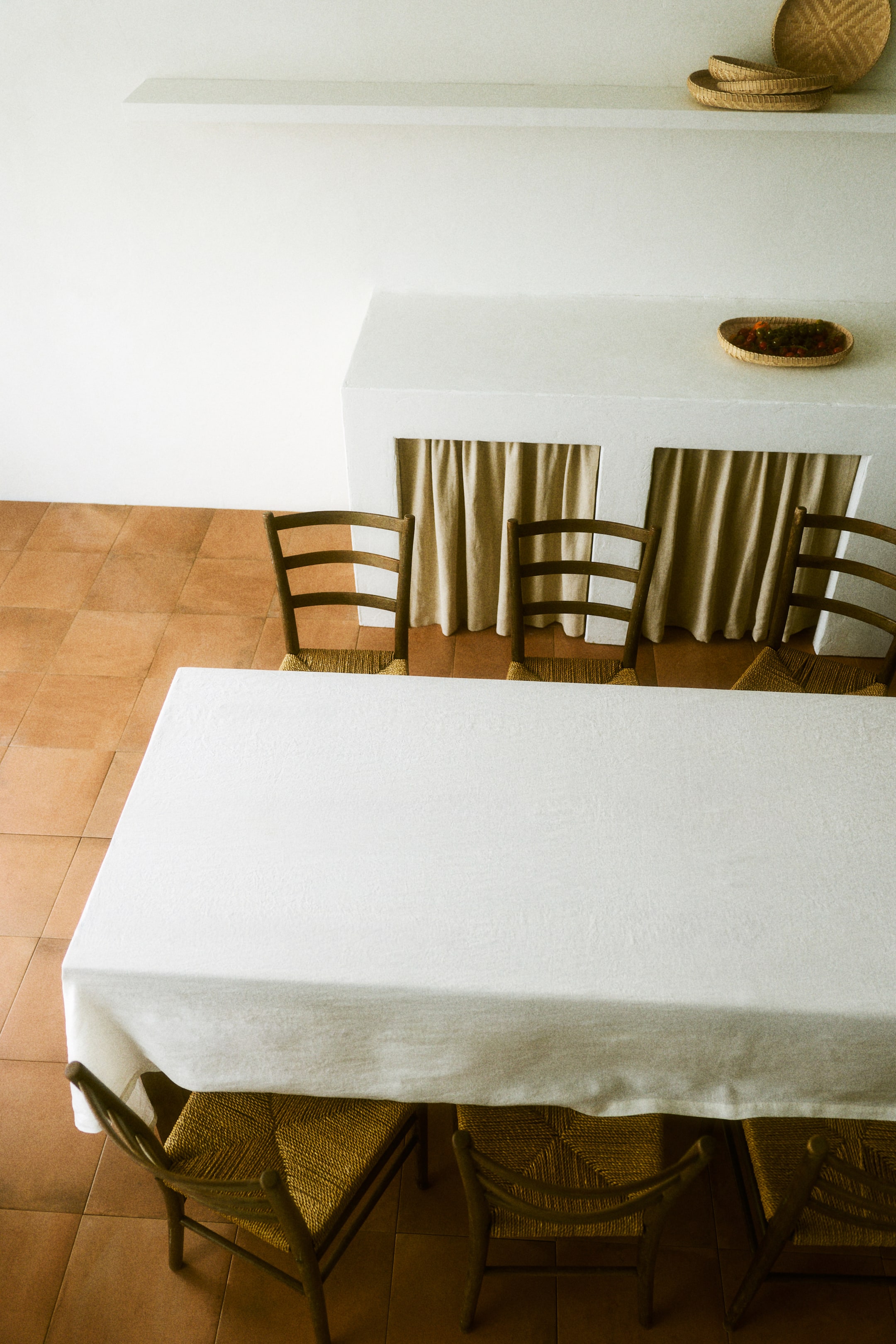 Größeres Bild anzeigen: Ein weißes Tischtuch zeigt eine dezente Leinenwebstruktur. Es ist mit einem sichtbaren 2,5 cm breiten Saum versehen, der sich sanft über einen rechteckigen Tisch legt.