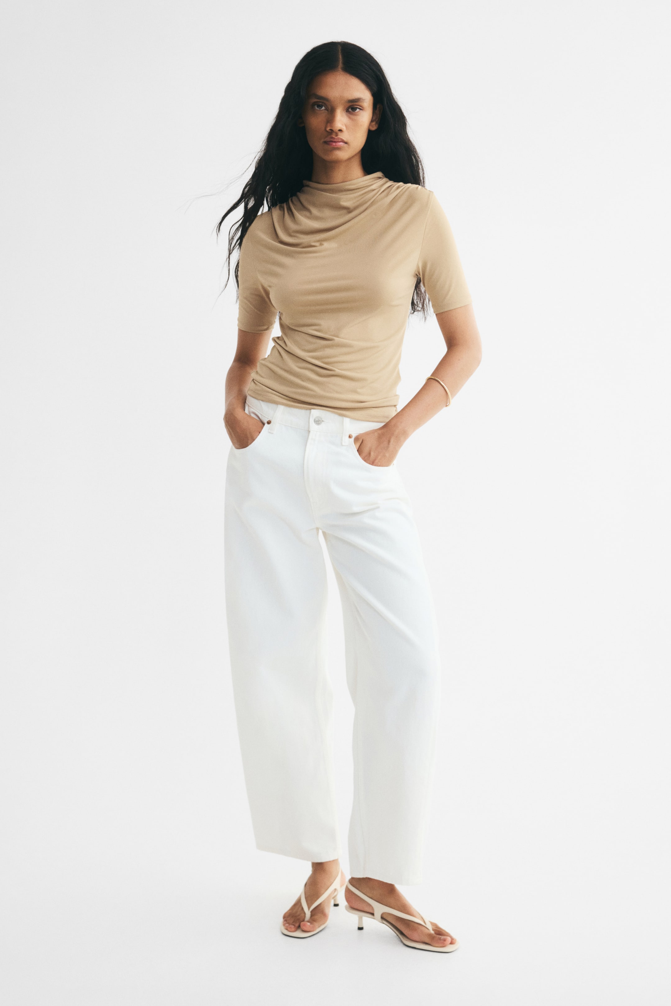 View larger image: The model is wearing a fitted top in stretch jersey, featuring gathered shoulders that create a draped effect, a stand collar, short sleeves, and a straight hem.