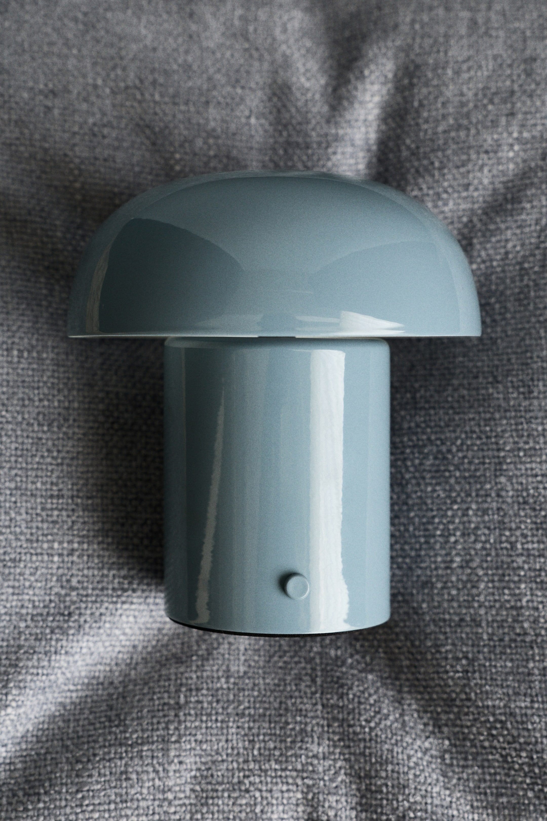Grösseres Bild ansehen: Eine staubige blaue Pilzlampe präsentiert einen glänzenden, gewölbten Schirm und einen zylindrischen Sockel, mit einem kleinen runden Bedienknopf, der an der Seite sichtbar ist.