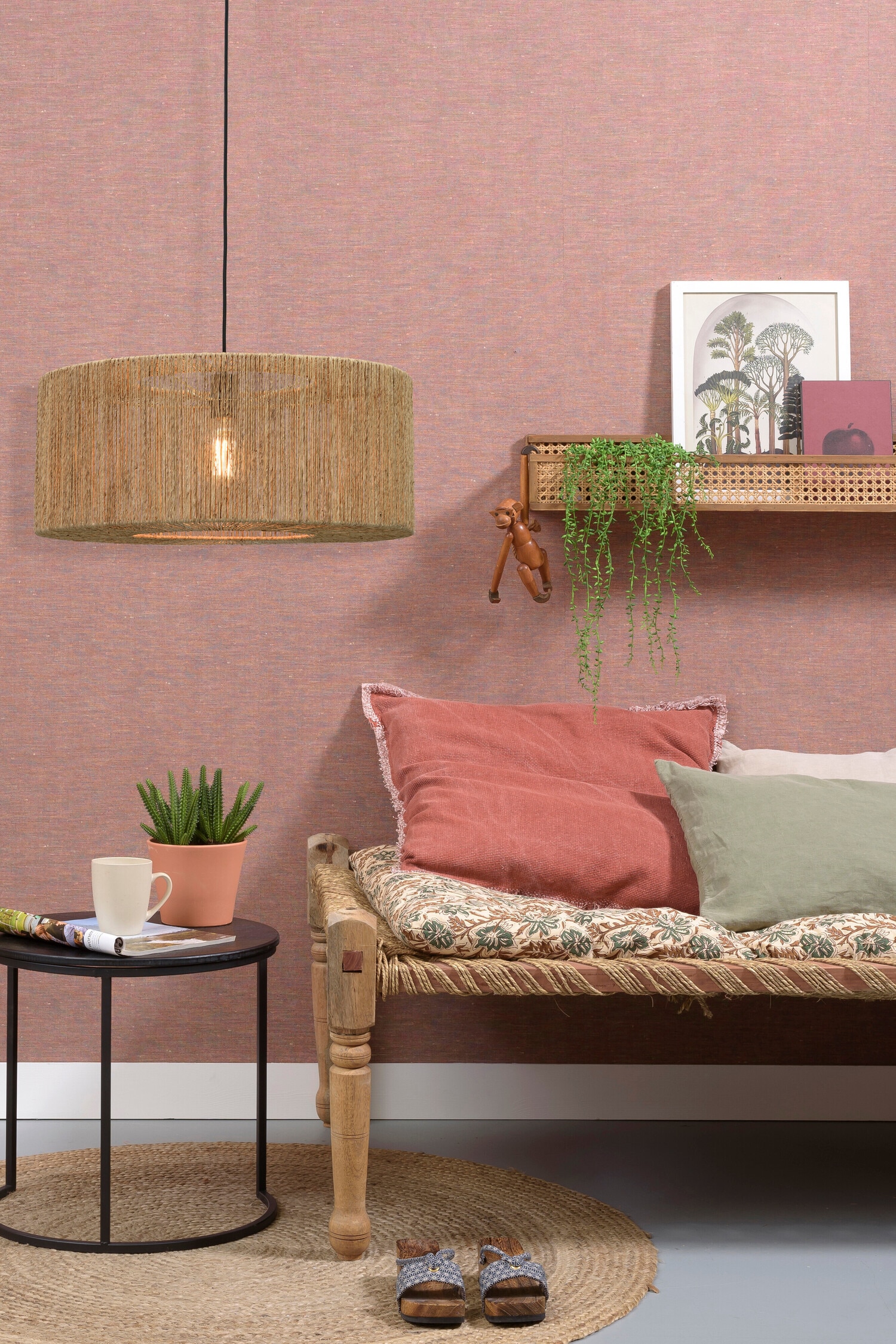 La suspension Iguazu est présentée de face, avec un large abat-jour tambour enveloppé de cordons de jute verticaux, étroitement espacés, dans une teinte beige naturelle. Une seule ampoule diffuse une lumière chaleureuse à travers l’abat-jour semi-transparent, suspendu par un fin cordon noir.