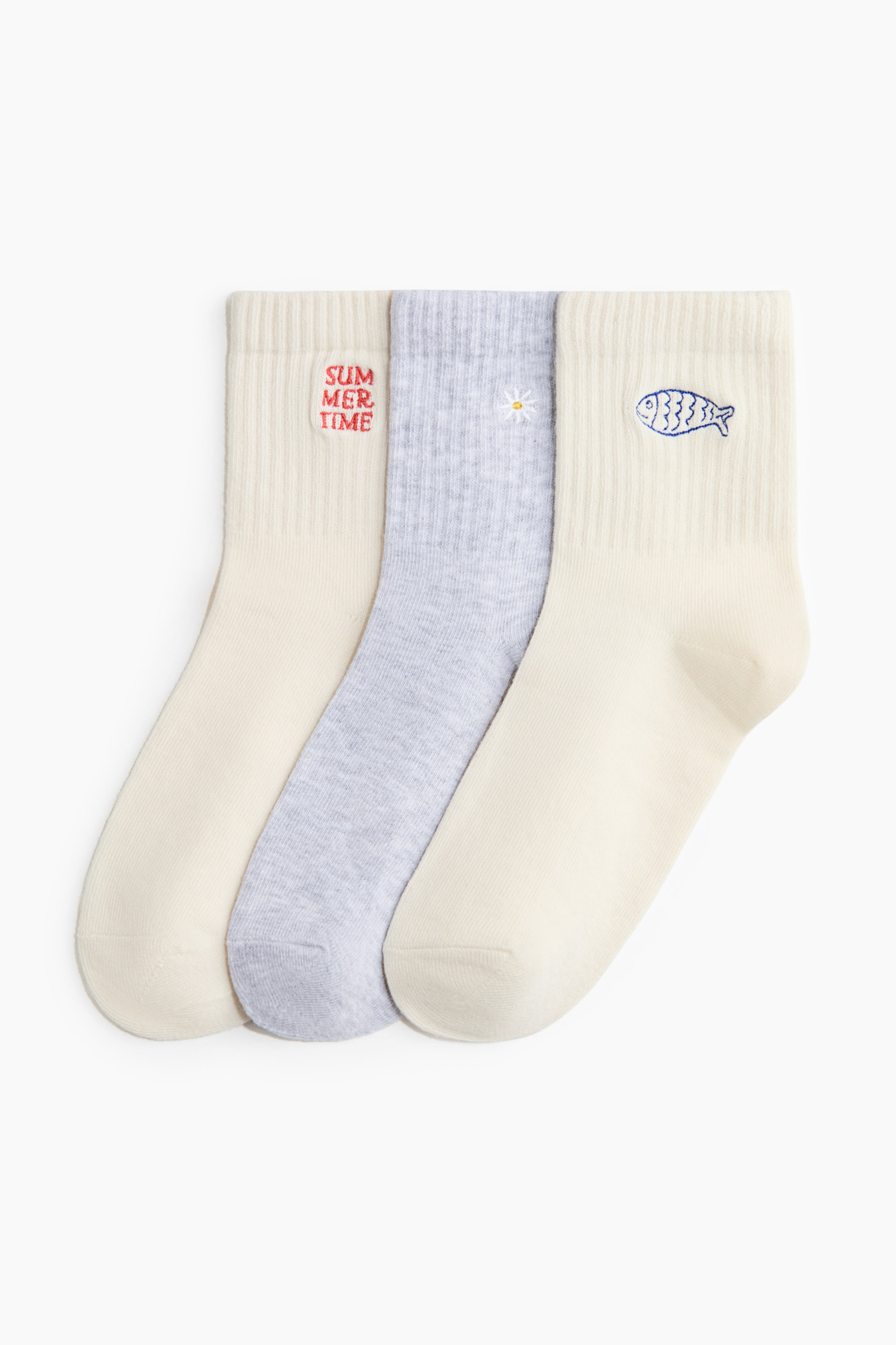 View larger image: A set of three socks crafted from a fine-knit cotton blend, featuring ribbed shafts and elasticized tops, is displayed from the front. The two socks on the outer sides are cream, while the one in the middle is light gray. Each sock showcases a unique embroidered design on its front shaft: "SUMMER TIME" in red on the left, a white daisy on the middle, and a blue fish on the right.