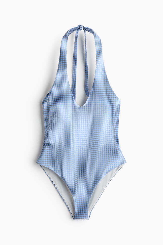 A one-piece swimsuit is displaying a blue and white small check pattern. It is featuring a halter neckline with straps tying at the back, a deep V-neck, and high-cut leg openings. - 1
