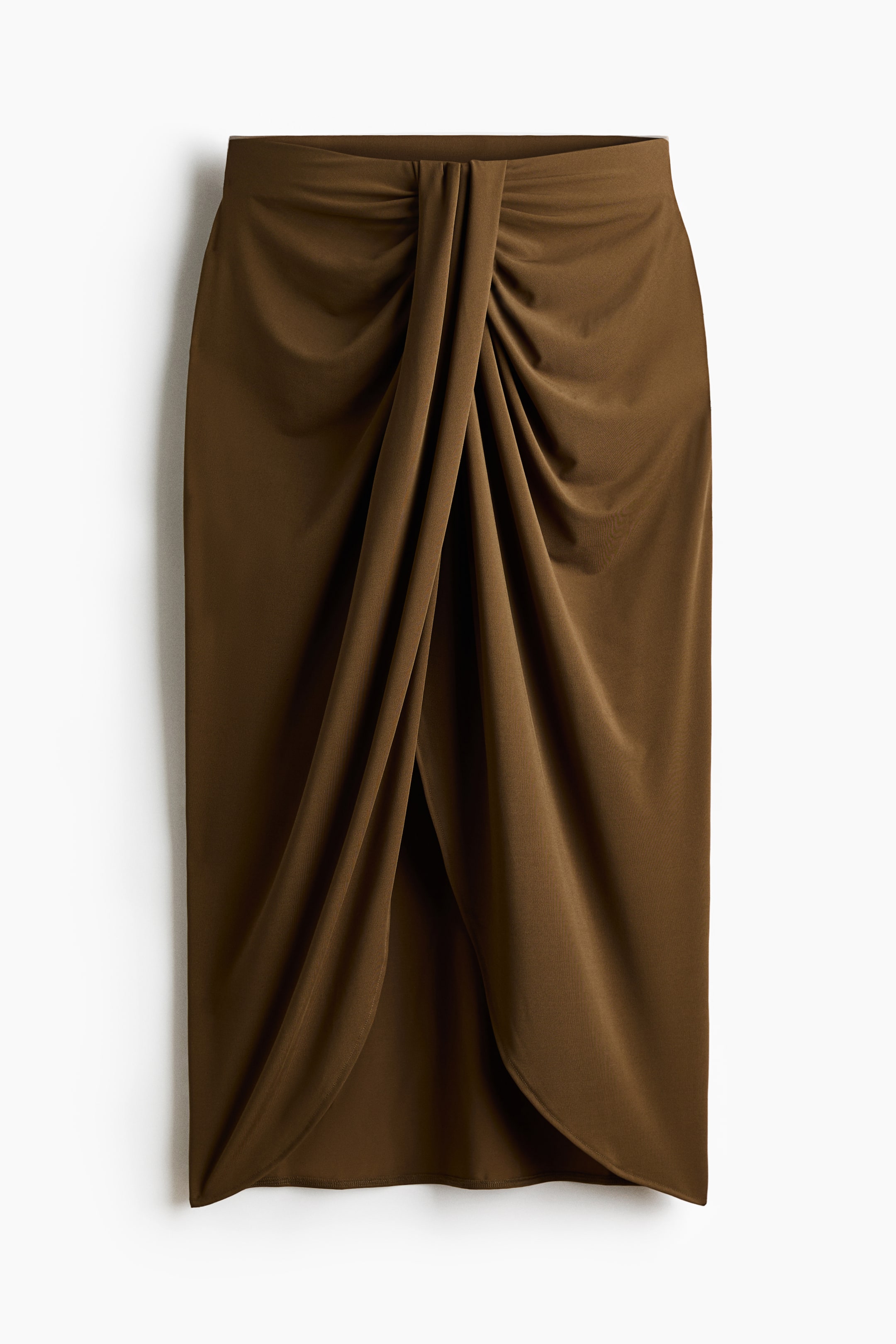 View larger image: A brown calf-length skirt in a soft jersey fabric is displayed from the front, featuring a high, elastic waistband. The front showcases a twisted detail that creates a draped effect, leading to an asymmetrical hem with a slit.