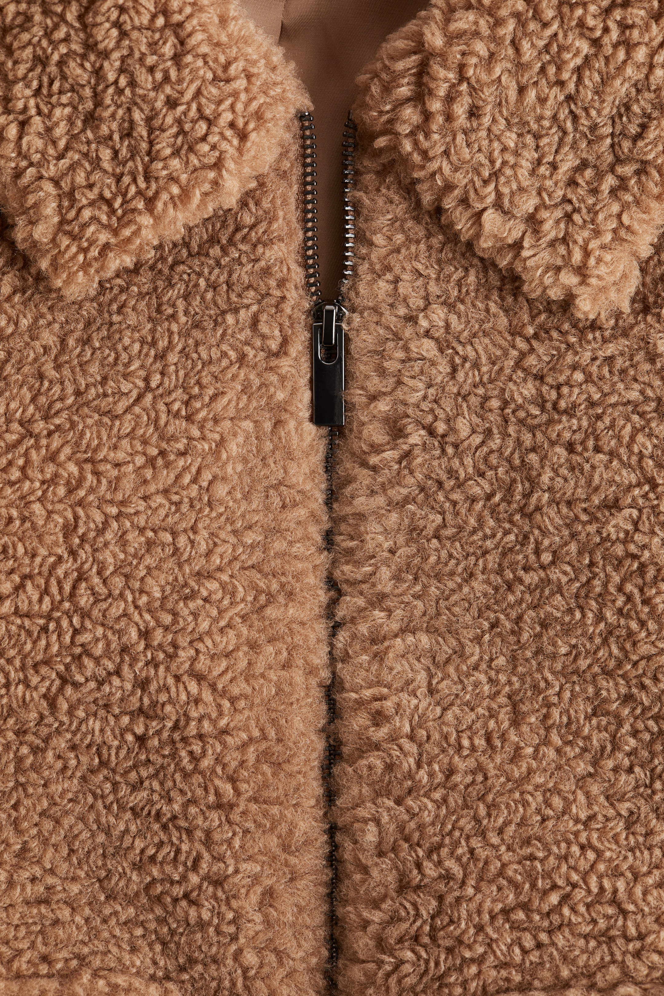 Voir une image plus grande: Une veste est dotée d'un tissu duveteux avec un col et d'une fermeture éclair en métal qui descend à l'avant.