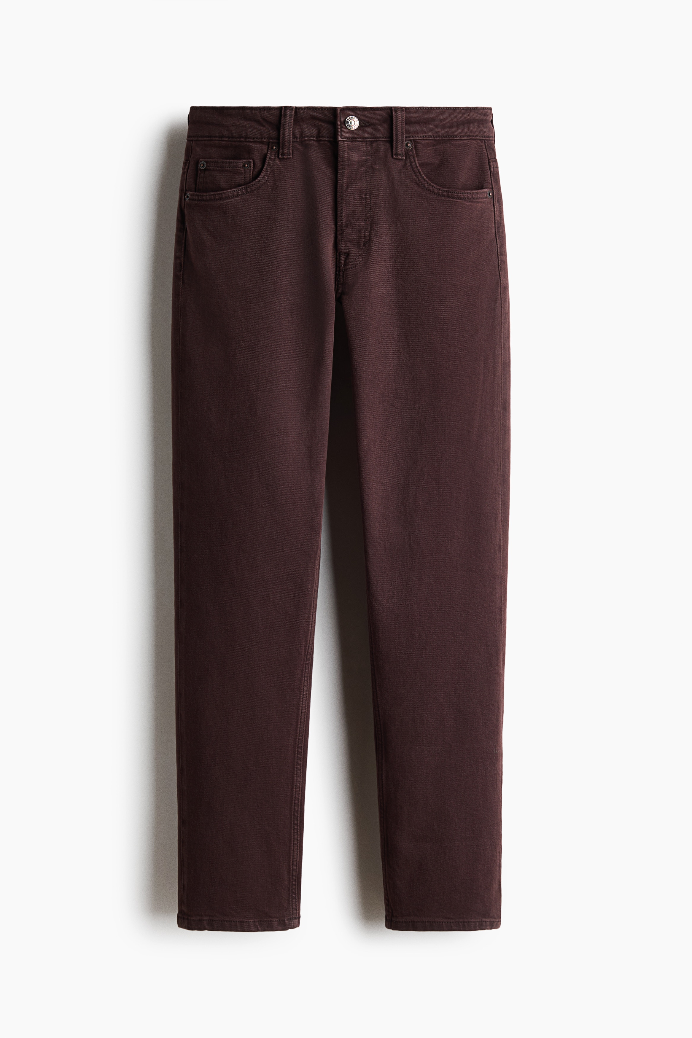 De model draagt donker bordeauxrode, recht gesneden denim jeans, met haar handen in de voorzakken. De jeans met normale taille en vijf zakken zijn gestyled met een zwarte leren jas en zwarte sandalen met hak.