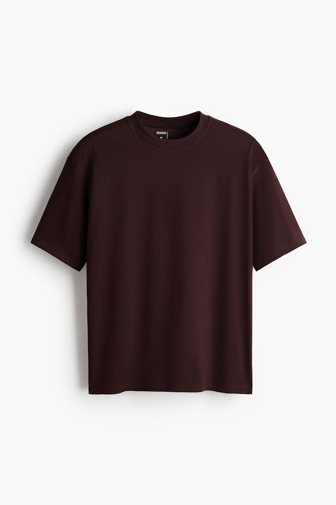 A dark brown, relaxed-fit T-shirt is presenting as front, featuring a round, rib-trimmed neckline, dropped shoulders, short sleeves, and a straight-cut hem. - 1