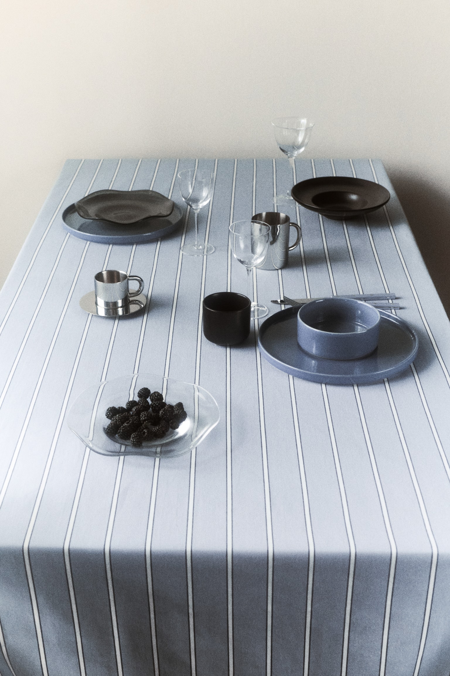 A folded light blue textile showcases vertical stripes, with fine dark blue lines alternating with broader white lines. A finished hem can be seen along the bottom edge. - 1