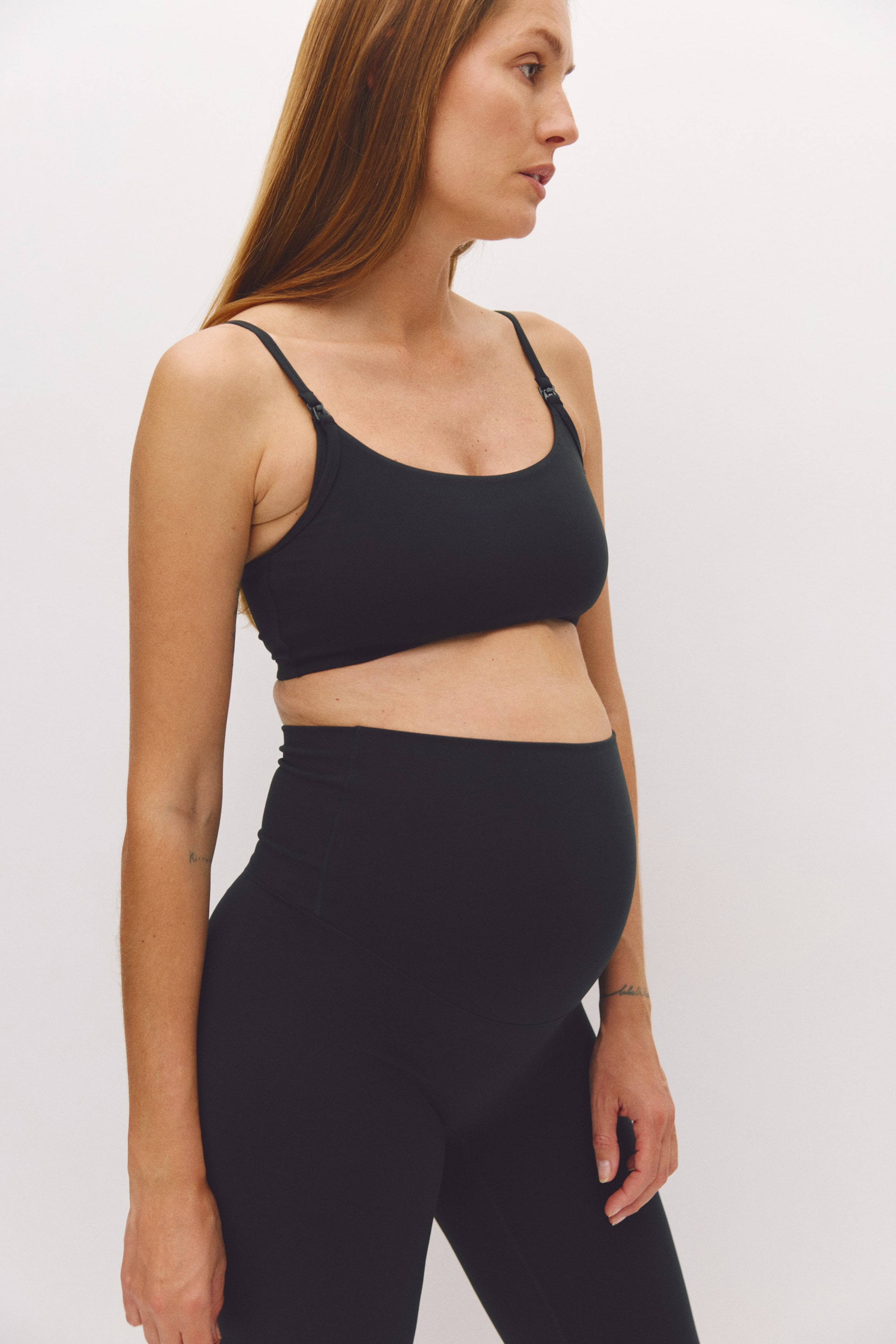 查看大圖: 模特兒穿著黑色 MAMA Medium Support Nursing Sports Bra,採用圓領領口、附哺乳扣環的細版可調式肩帶,以及寬版下胸圍設計。此胸罩搭配同款黑色高腰孕婦緊身褲。