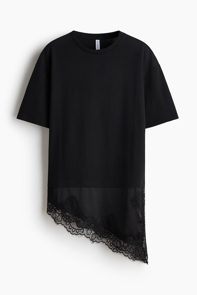 A black short-sleeved t-shirt is presented flat, featuring a crew neck and a relaxed fit. Its asymmetrical bottom hem is displaying a black satin panel, with intricate black lace trimming its edge. - 1