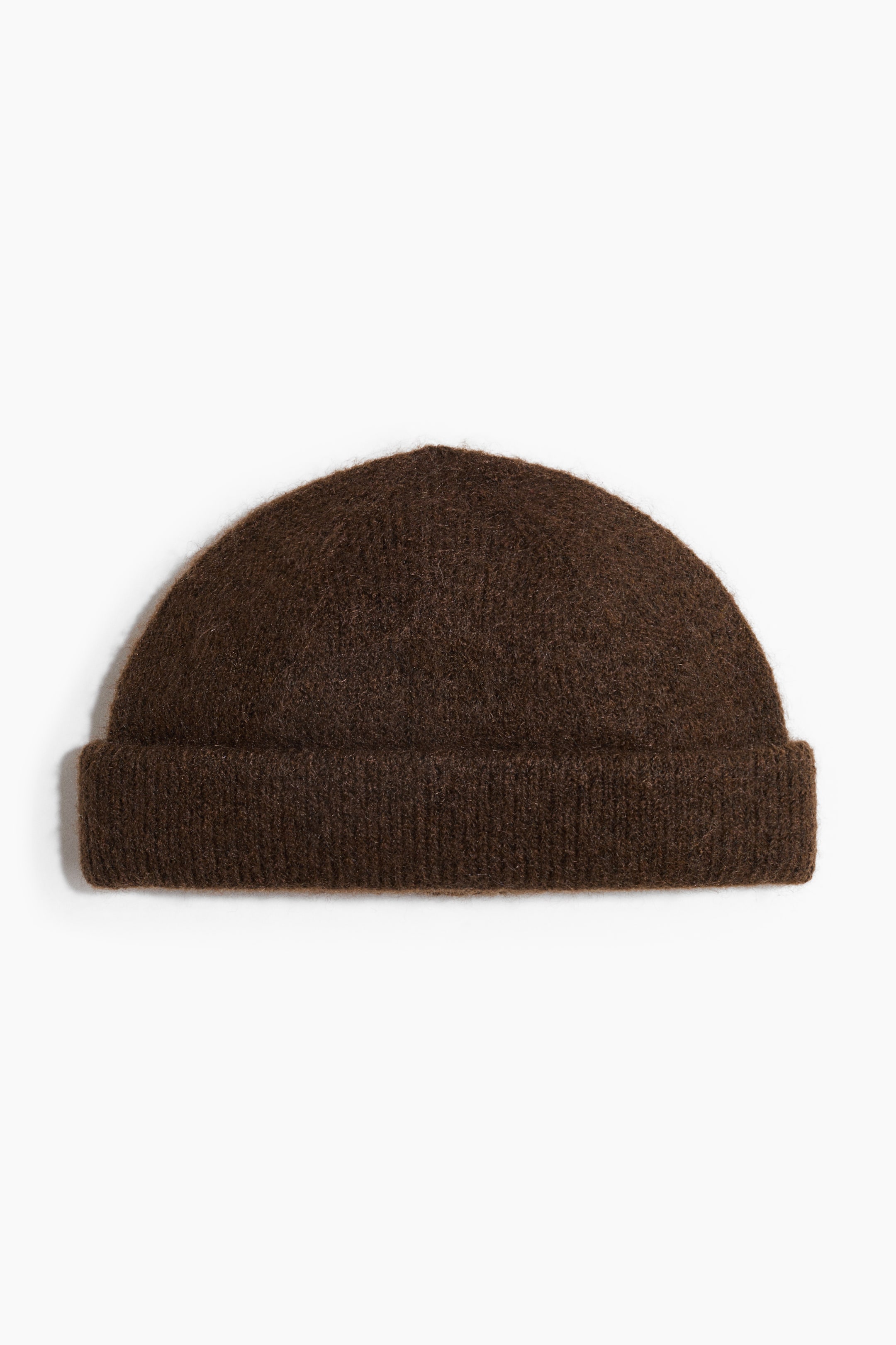View larger image: A dark brown knit beanie is shown from the front, featuring a rounded, dome-shaped crown and a thick, ribbed cuff turned up at the brim. The beanie is made of a fuzzy, textured knit material.