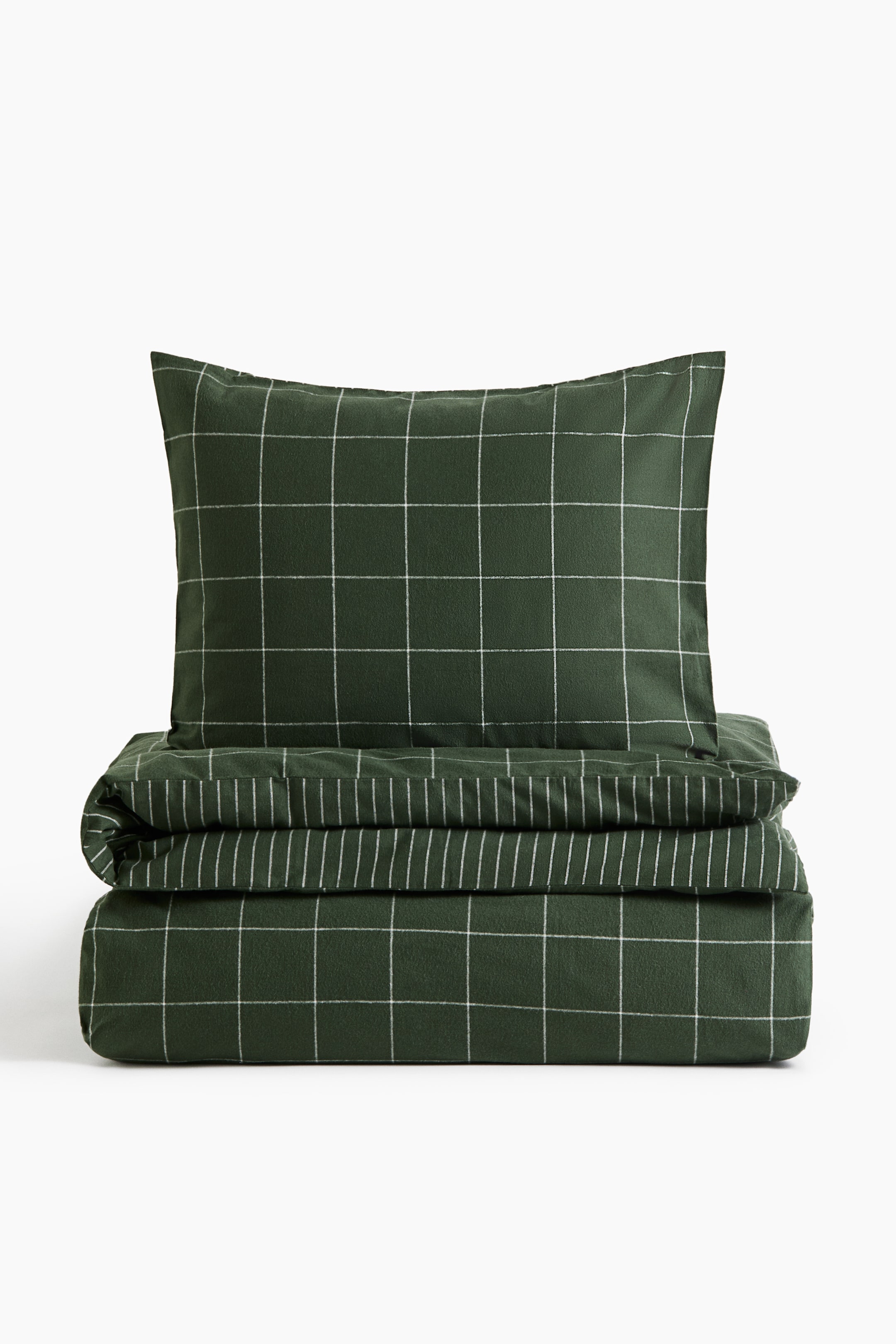 View larger image: A single quilt cover set in dark green cotton flannel is shown from the front, featuring a white windowpane check pattern. The set is presenting an upright pillowcase resting on top of a folded quilt cover, which is showing a coordinating white vertical stripe pattern on its reverse side.