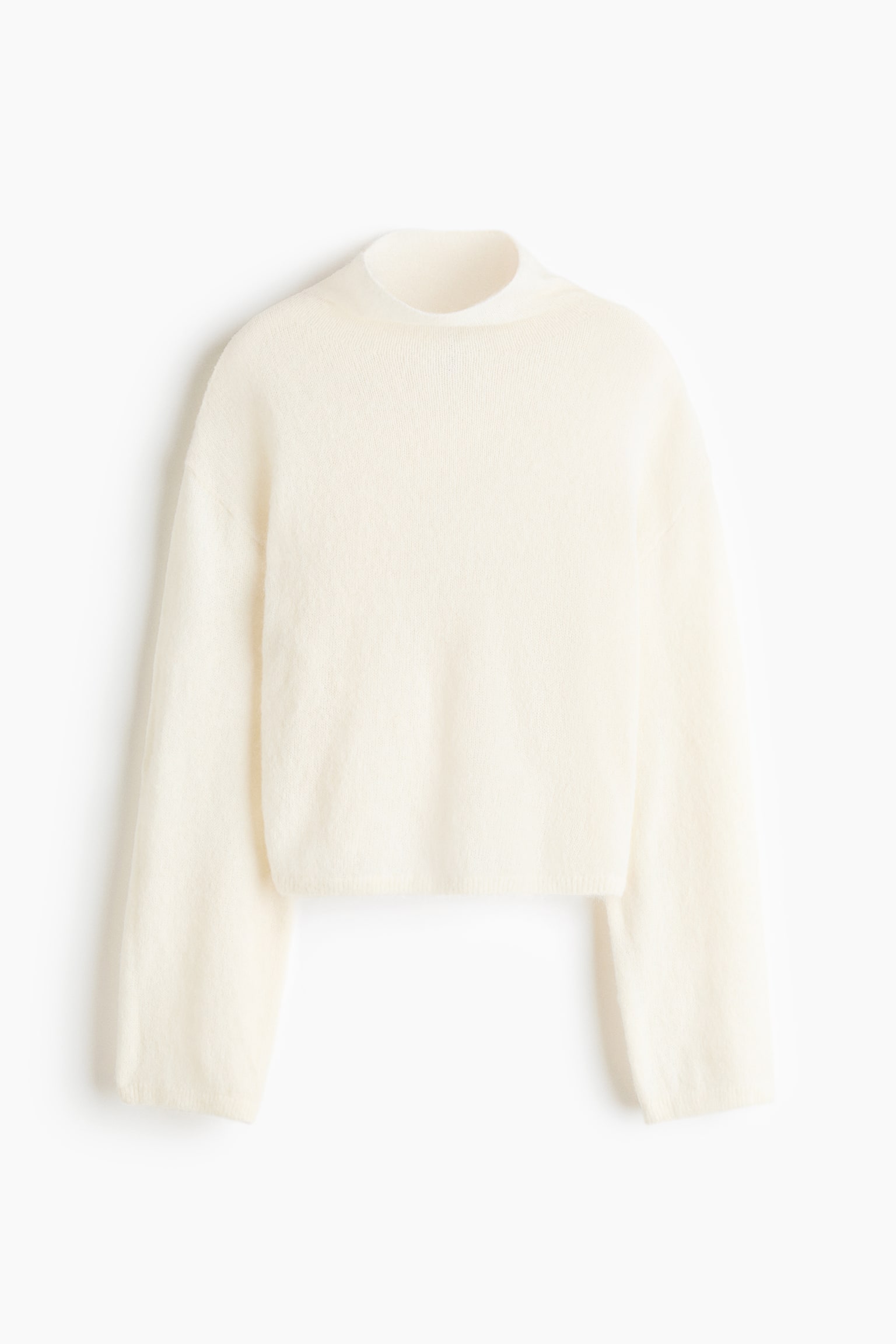 A cream-coloured knit sweater is facing front, showing a mock neck, dropped shoulders, and long, wide sleeves. The sweater features a soft, fuzzy knit texture and a relaxed, cropped silhouette.