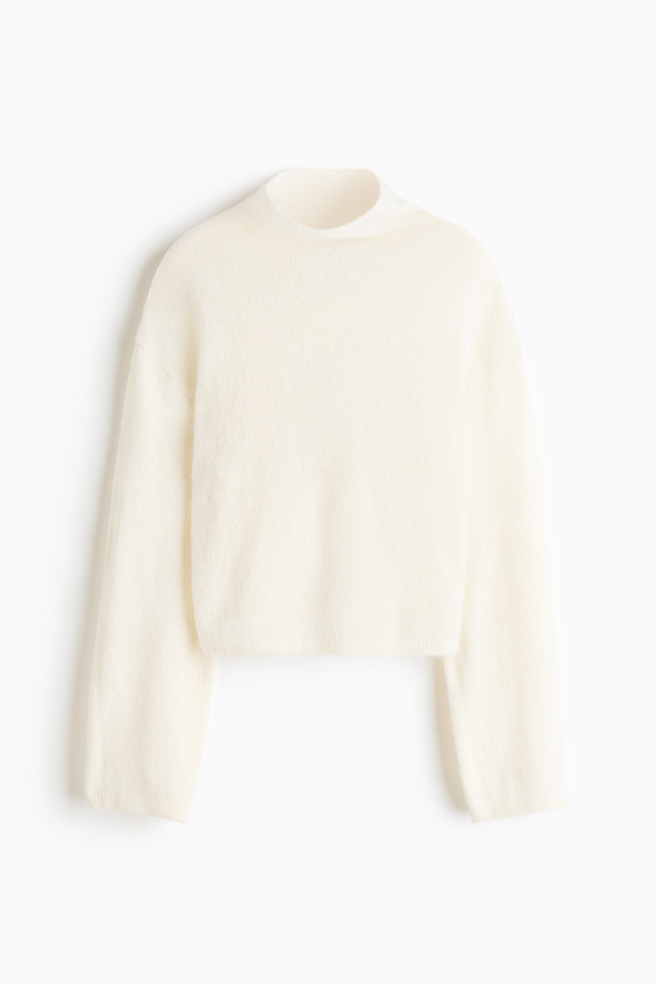 View larger image: A cream-coloured knit sweater is facing front, showing a mock neck, dropped shoulders, and long, wide sleeves. The sweater features a soft, fuzzy knit texture and a relaxed, cropped silhouette.