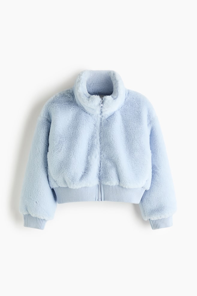 En lyseblÃ¥ teddyjakke ses forfra og fremhÃ¦ver en blÃ¸d, struktureret ydre i faux fur med hÃ¸j stÃ¥krave og en matchende lynlÃ¥s foran. Jakken har sÃ¦nkede skuldre, lange Ã¦rmer samt brede, elastiske ribkantede manchetter og nederkant. - 1